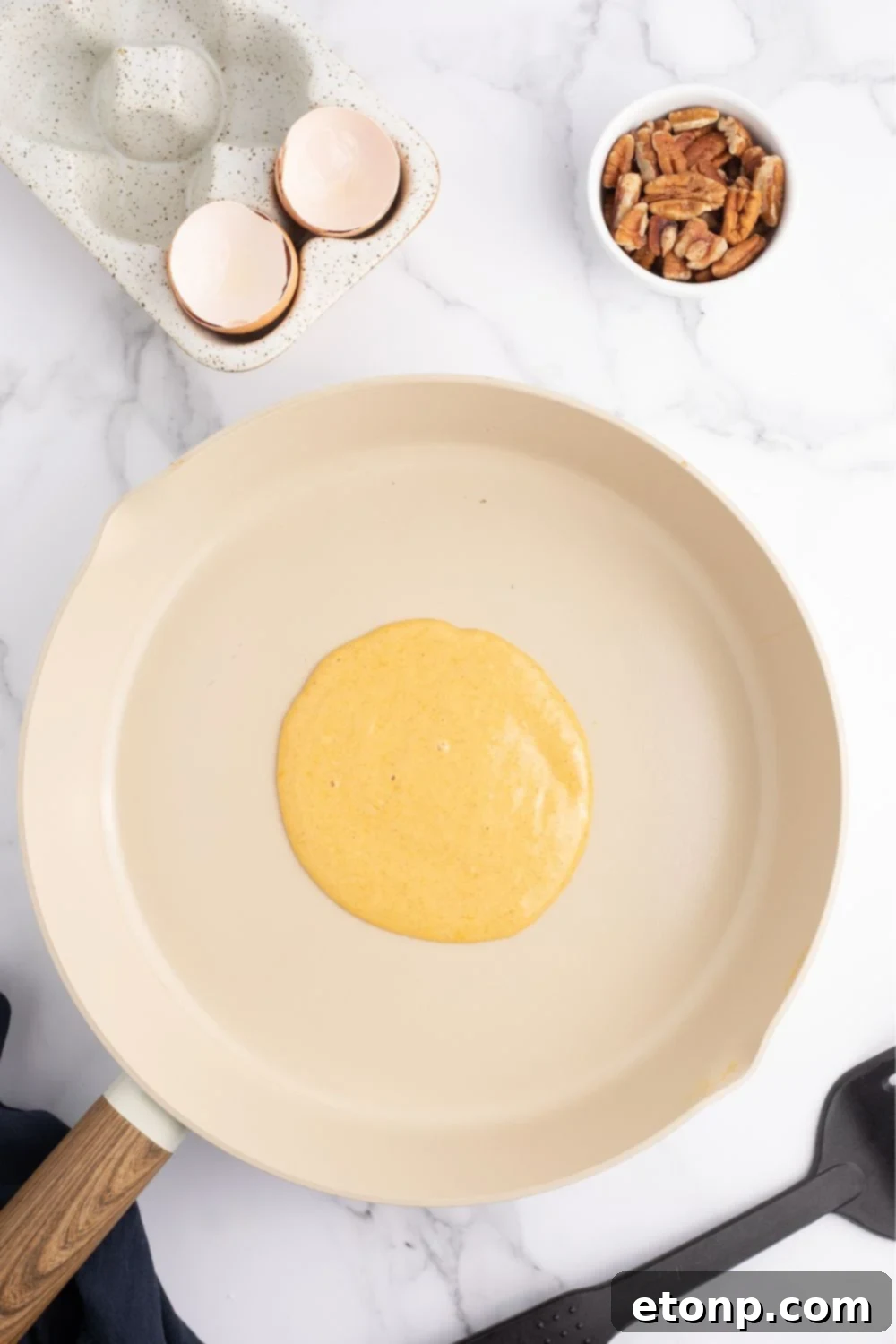 Raw pancake batter cooking in a skillet