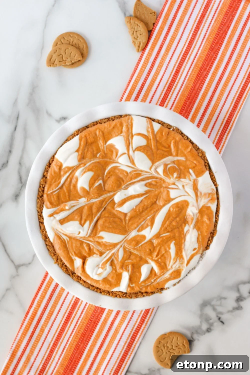 A close-up of a beautifully swirled pumpkin ice cream pie, showing the artistic blend of the two ice cream mixtures before freezing.