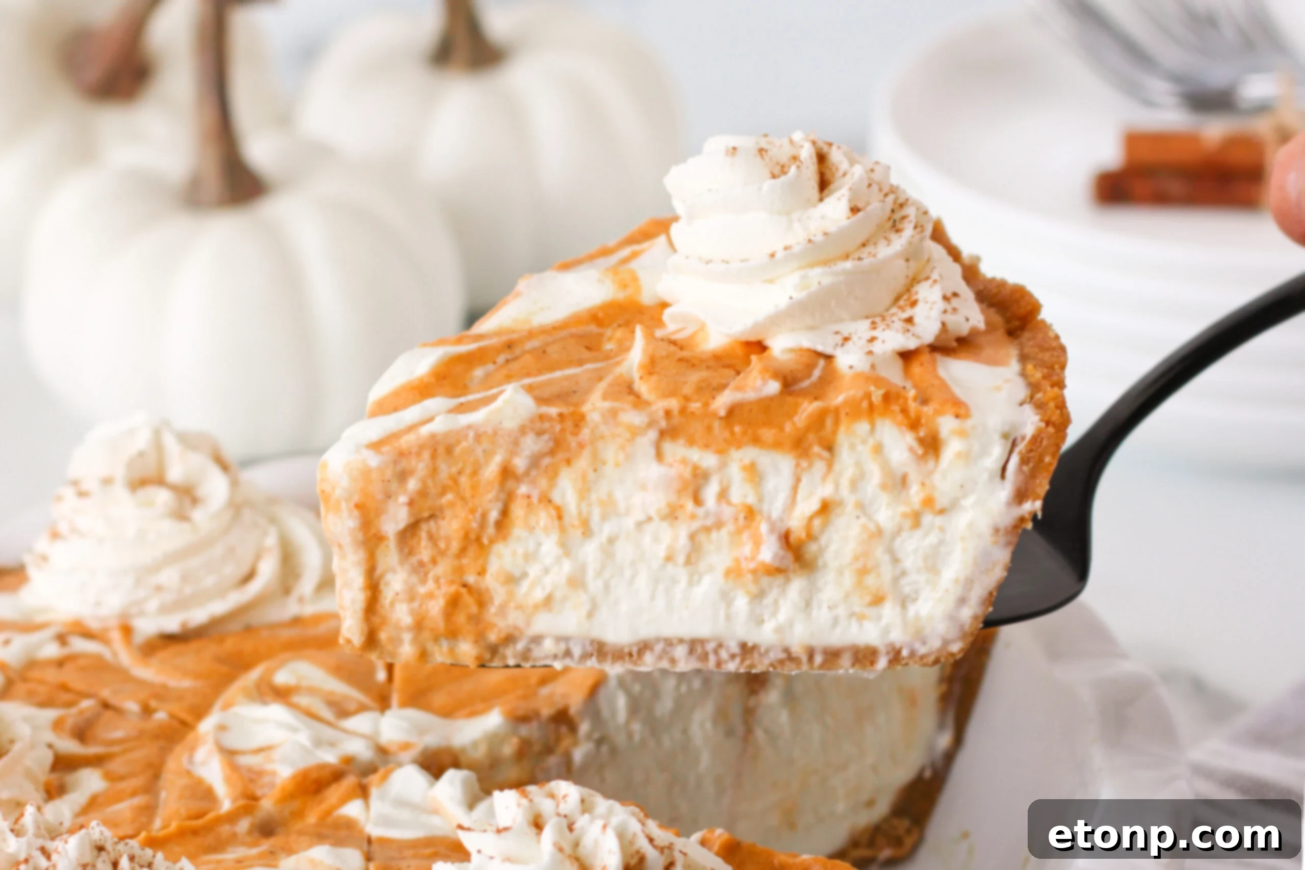 A delectable slice of Pumpkin Ice Cream Pie being carefully lifted from a white baking dish onto a serving spoon, ready to be enjoyed.