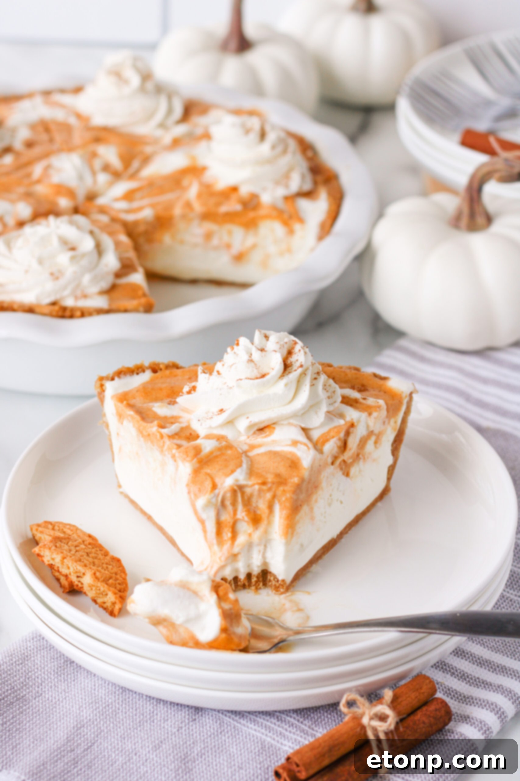 A pristine slice of Pumpkin Ice Cream Pie on a white plate, with a small bite missing, tempting anyone who sees it.