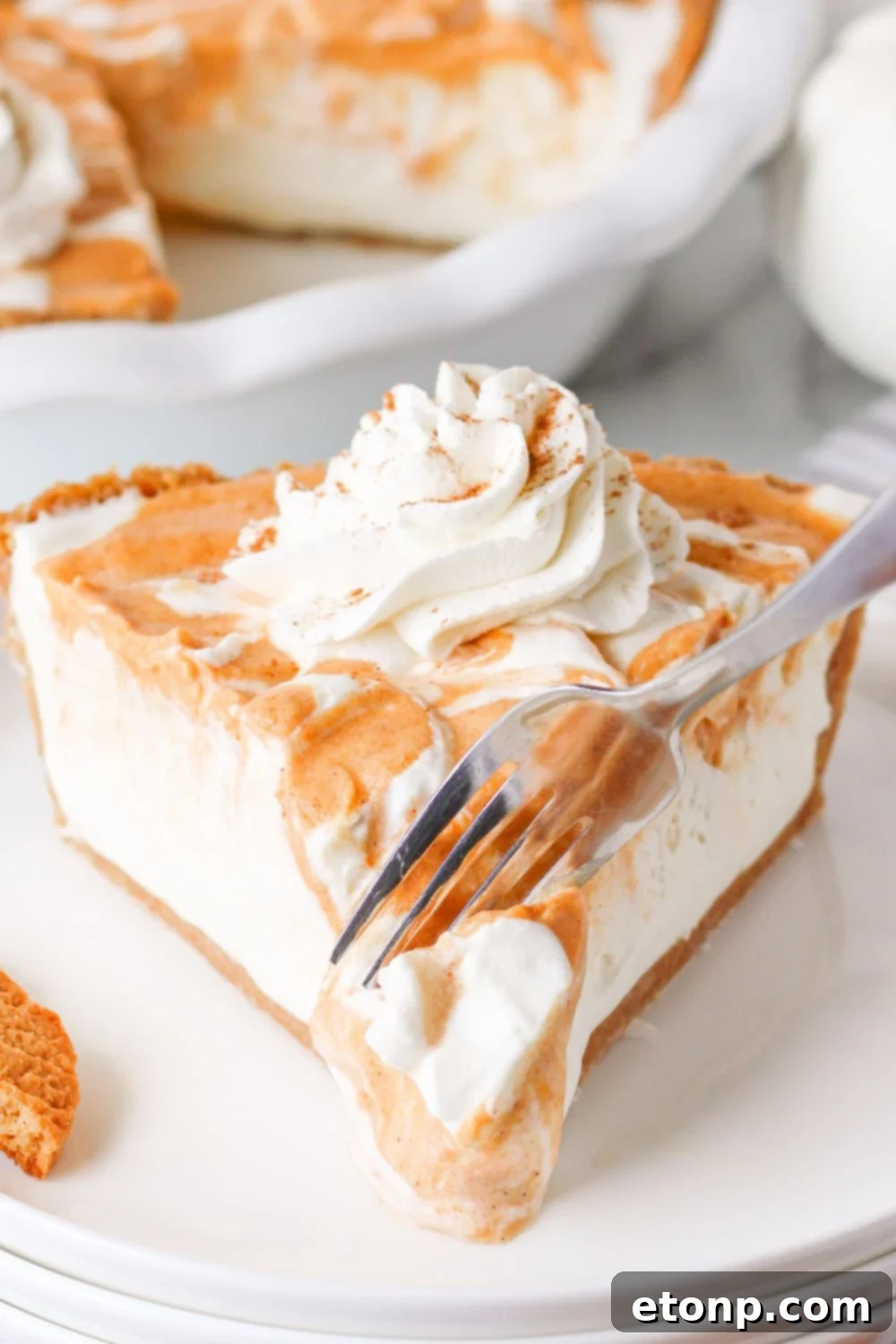 A fork gracefully slicing into a piece of pumpkin ice cream pie, illustrating its perfectly set and creamy texture.