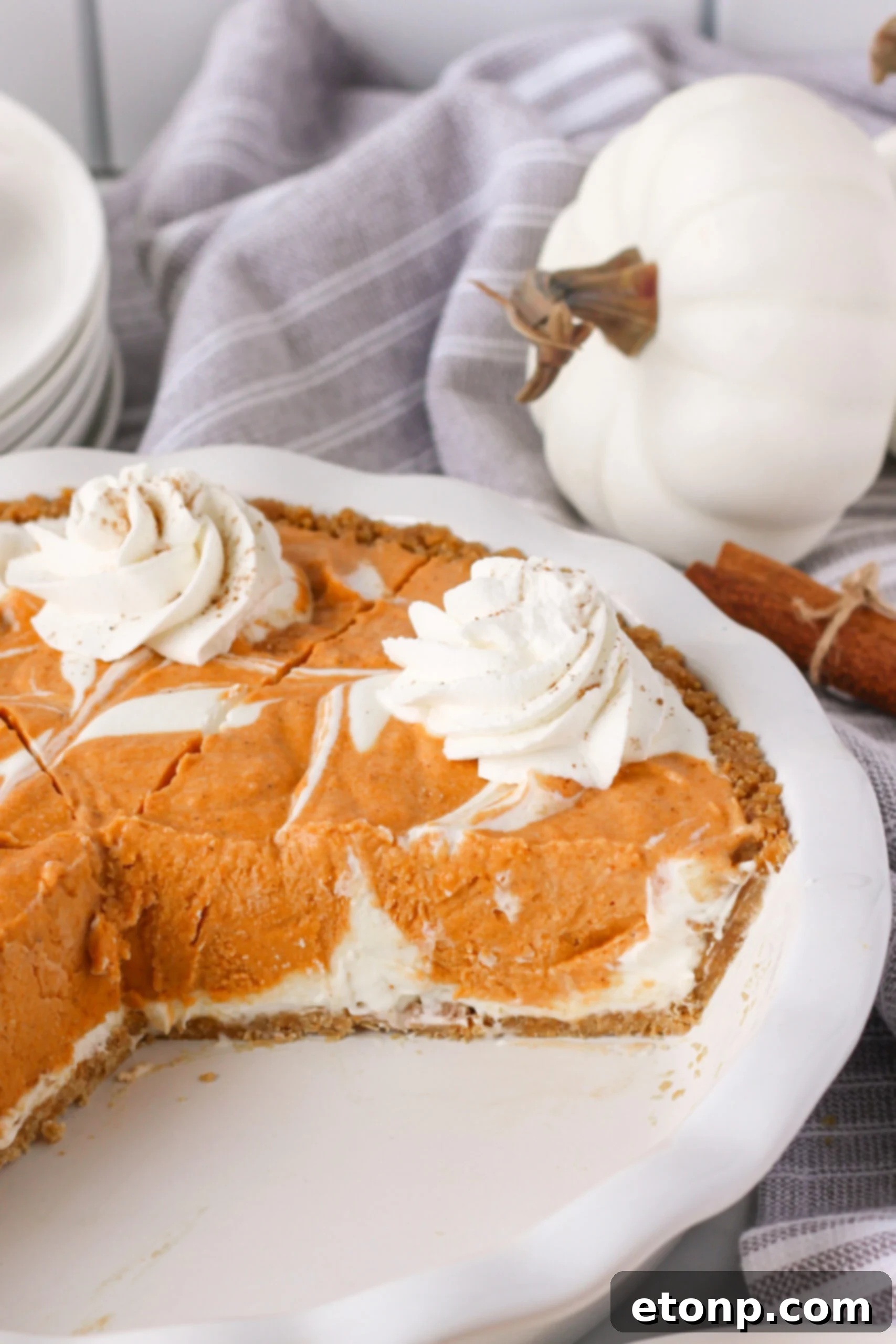 A Pumpkin Ice Cream Pie in a white baking dish with a couple of slices already removed, indicating its popularity and deliciousness.