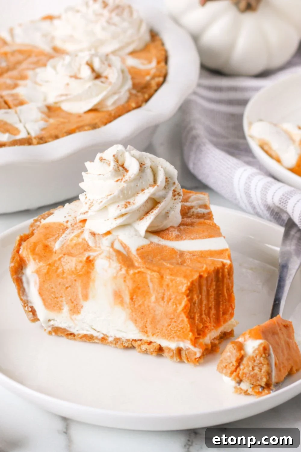 A close-up shot of a slice of pumpkin ice cream pie on a plate, with a small bite taken, revealing the delightful inner layers and inviting texture.
