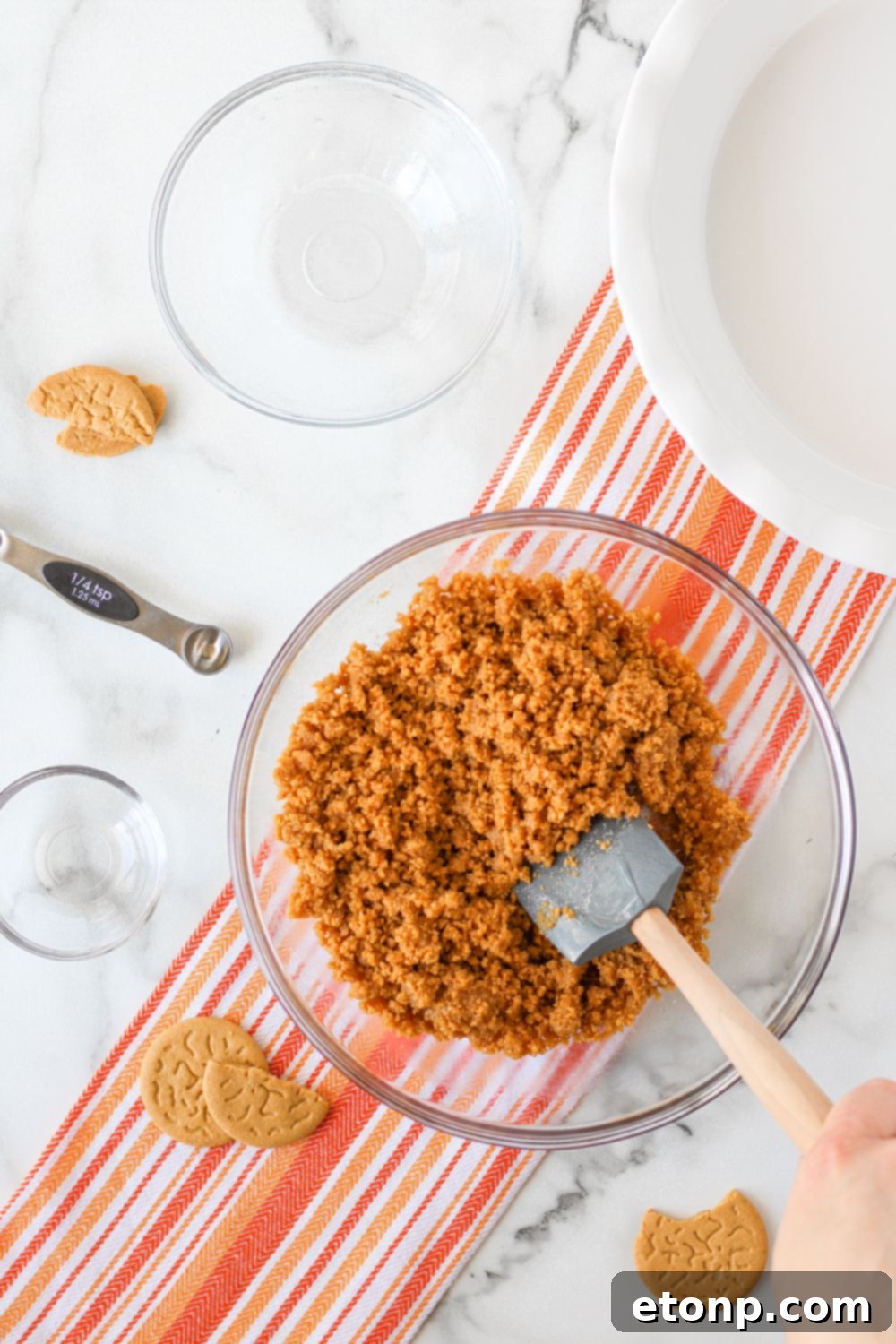 A glass bowl filled with the finely crushed gingersnap cookie mixture, perfectly blended with butter and sugar, awaiting assembly.