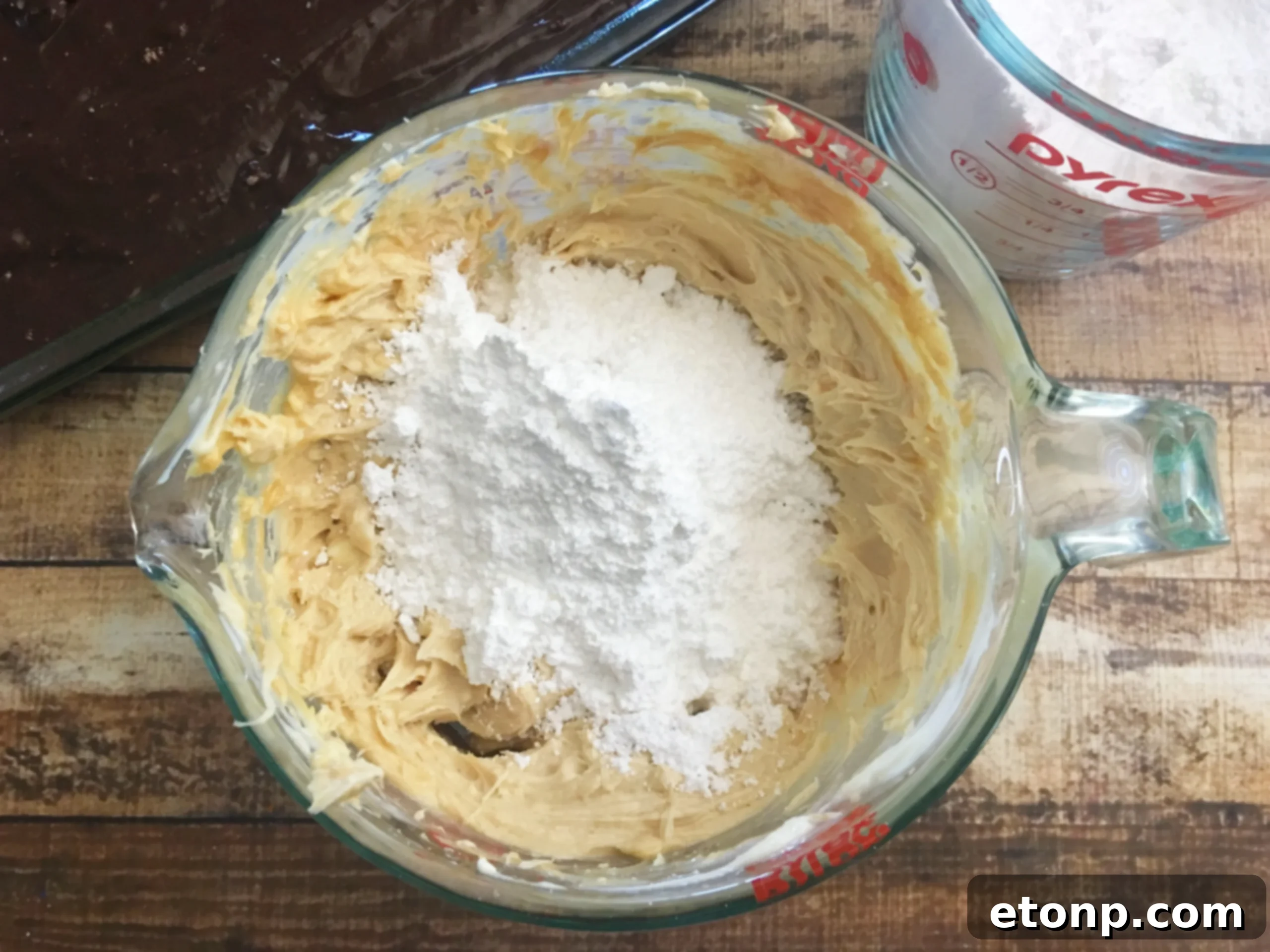 Ingredients for Peanut Butter Earthquake Cake laid out: cake mix, butter, cream cheese, peanut butter, vanilla, powdered sugar, chocolate chips, and Reese's cups