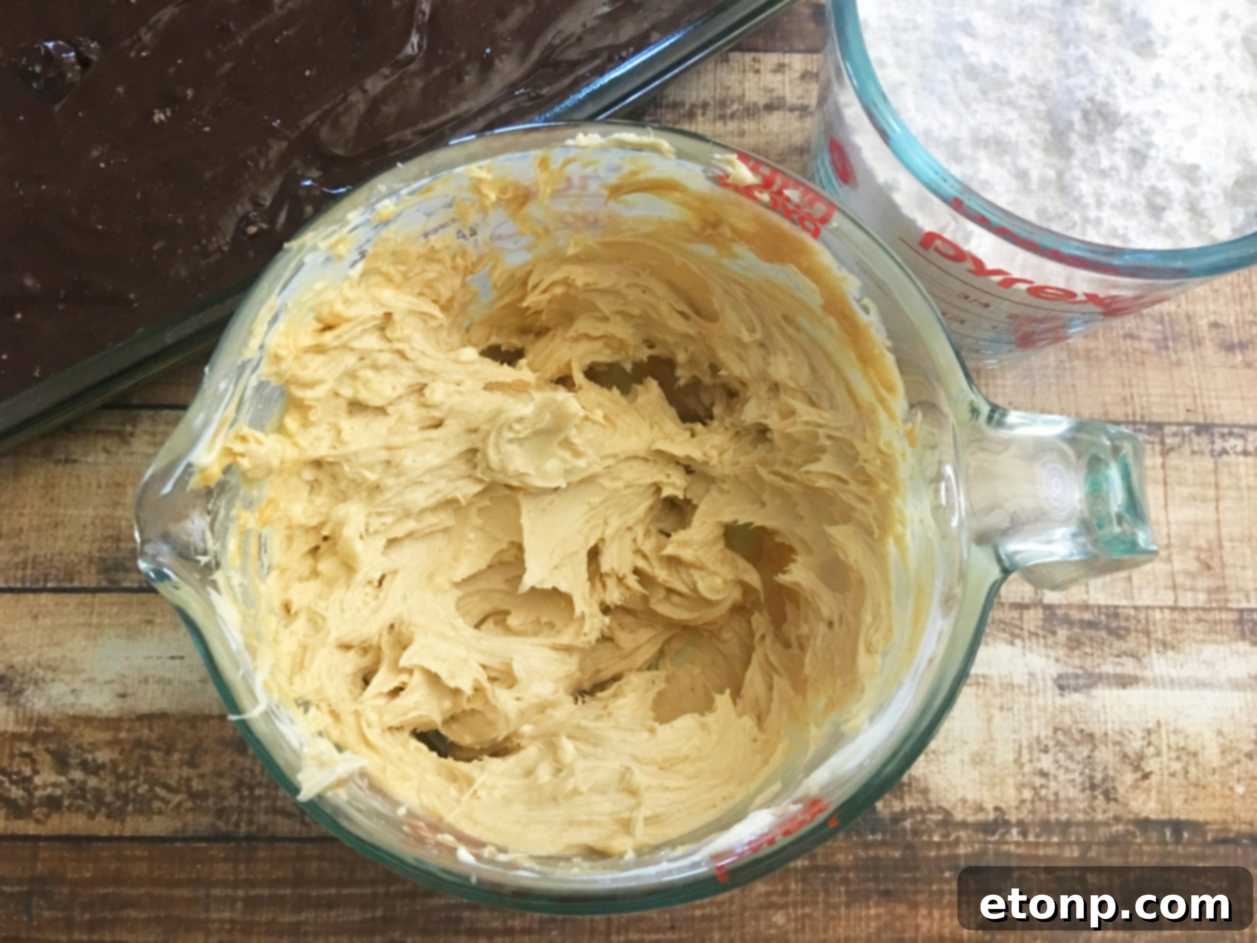 Mixing cream cheese, butter, peanut butter, and vanilla in a bowl for the cake topping