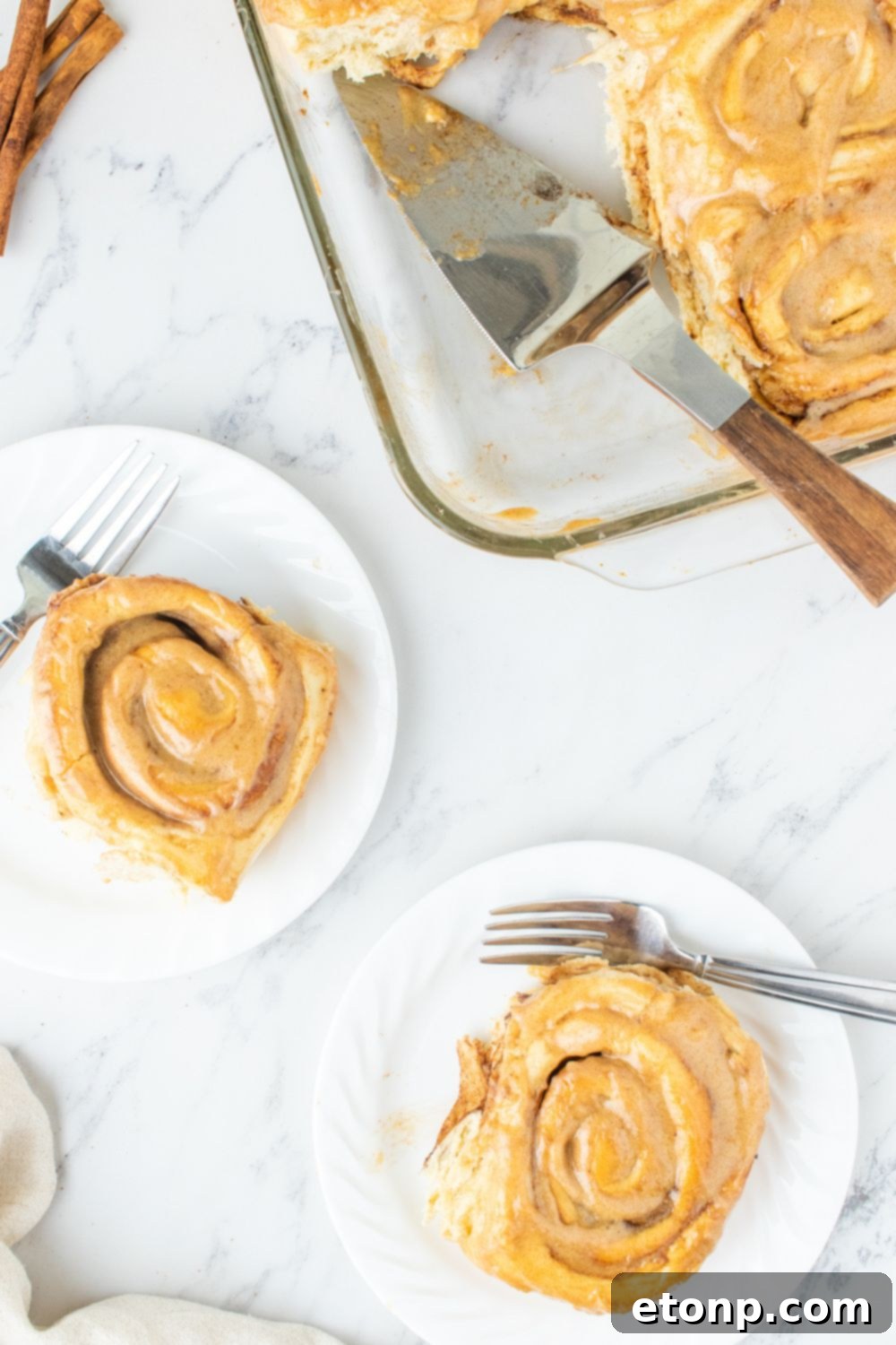 Two plates with pumpkin spice cinnamon rolls, beautifully frosted and ready to eat