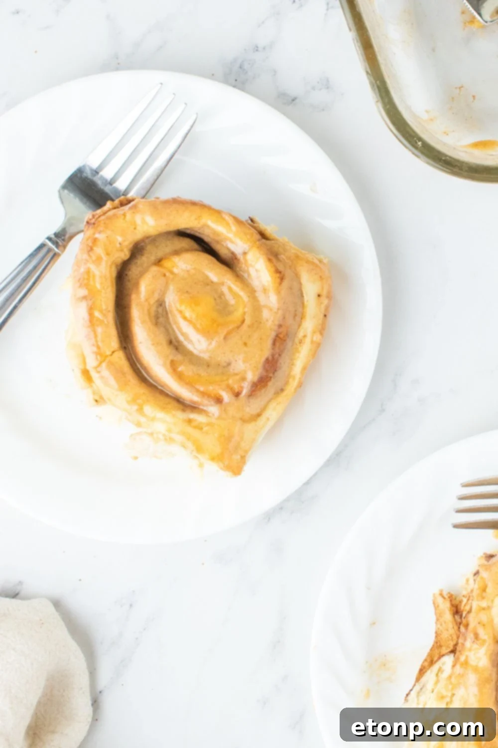 Multiple pumpkin rolls on plates, showcasing the rich frosting and golden crust