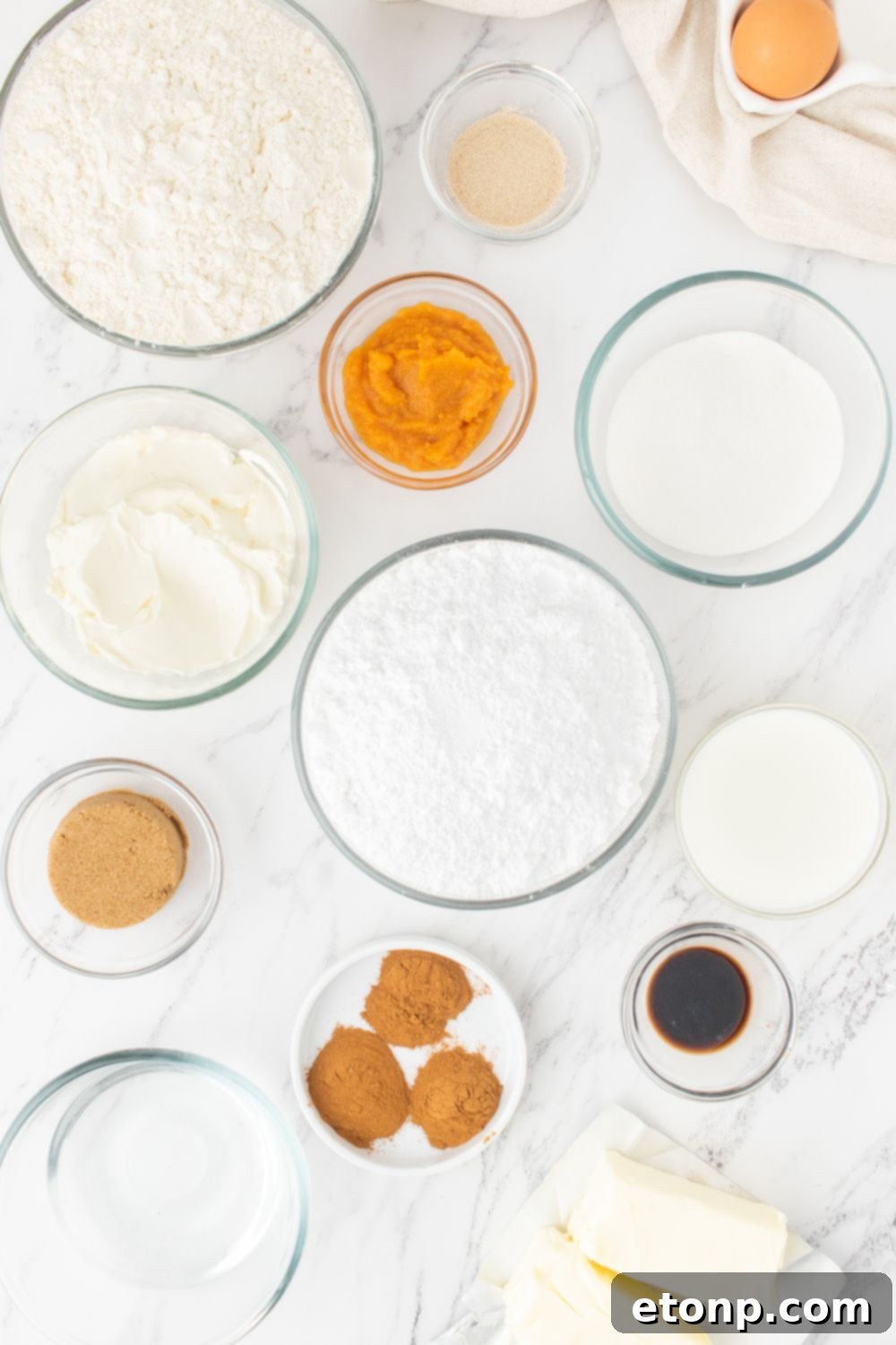 Various ingredients for cinnamon rolls displayed in bowls on a kitchen counter
