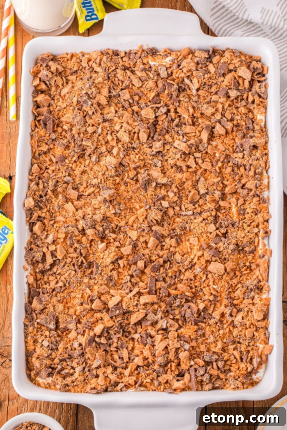 overhead look of poke cake in pan with butterfinger candy on top 