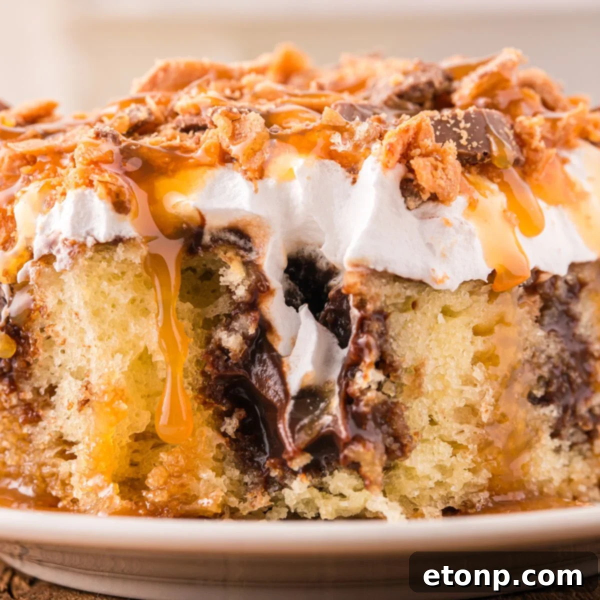 Butterfinger Poke Cake on plate with a bite taken out of it