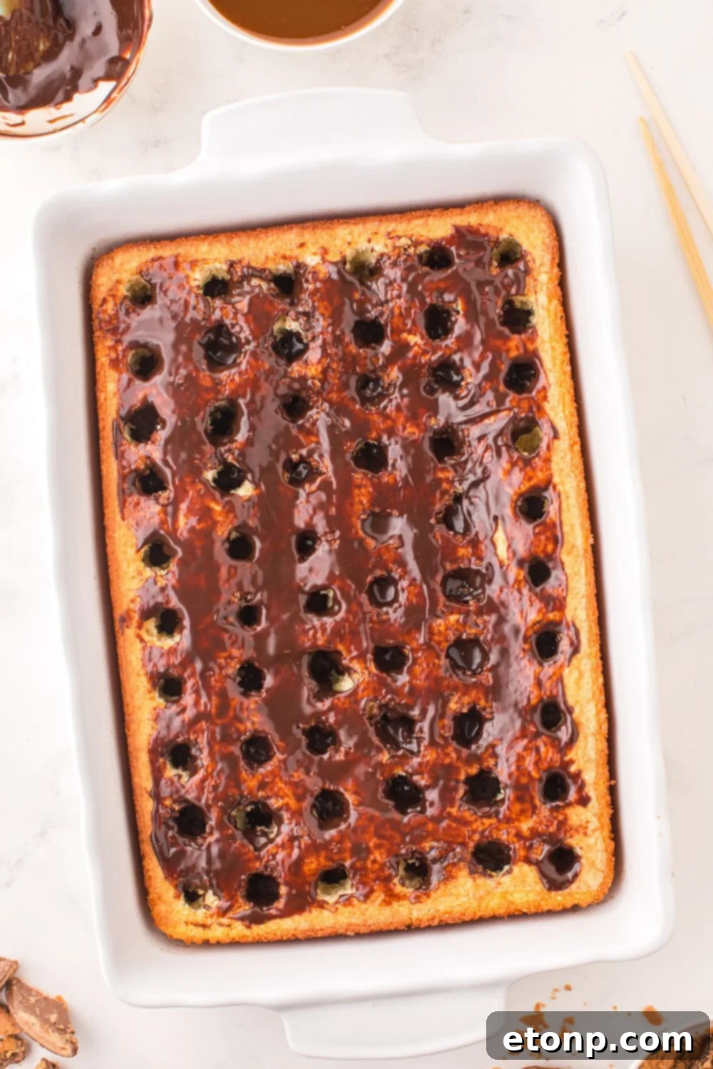 hot fudge spread allover the poke cake 