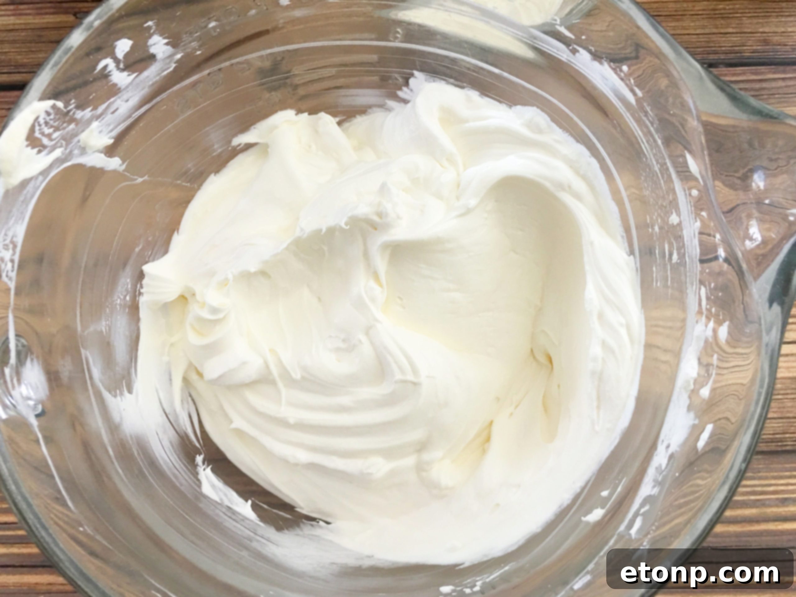 Whipped topping being spread over the pumpkin pudding layer, completing the dessert assembly.