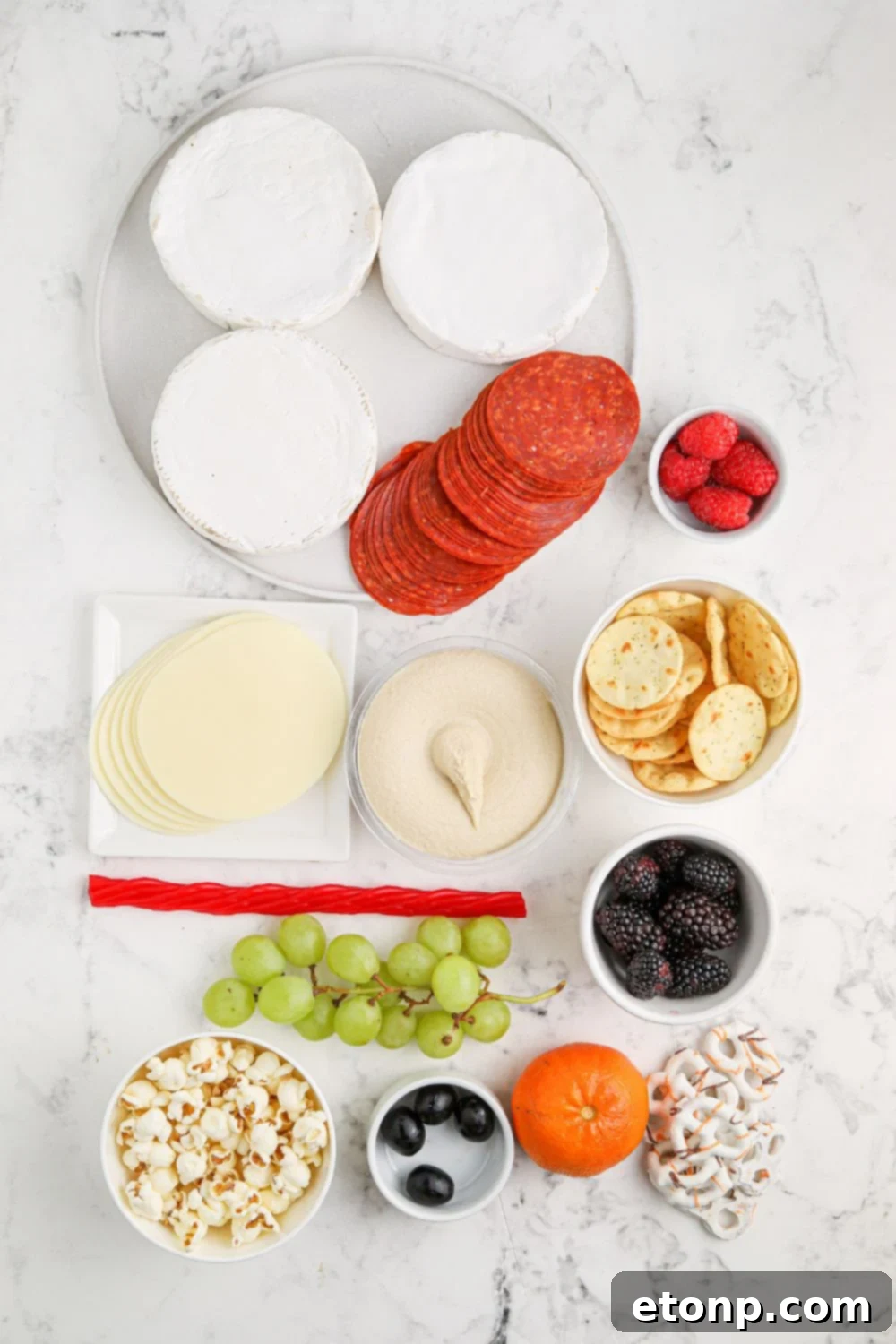 brie, and other ingredients to assemble charcuterie board on table