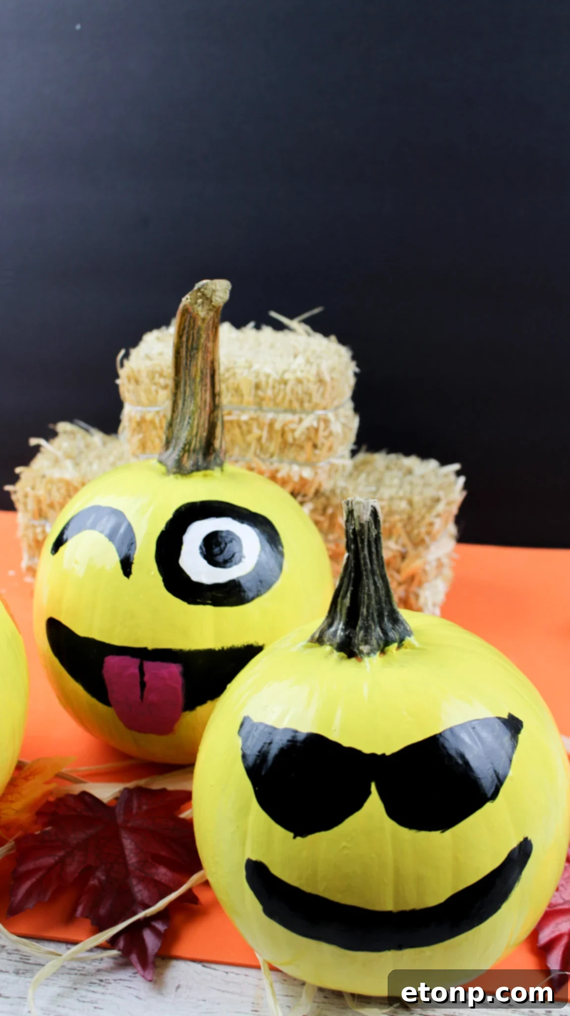 A vibrant yellow pumpkin painted with the 'heart eyes' emoji face, featuring red hearts for eyes and a wide, loving smile.
