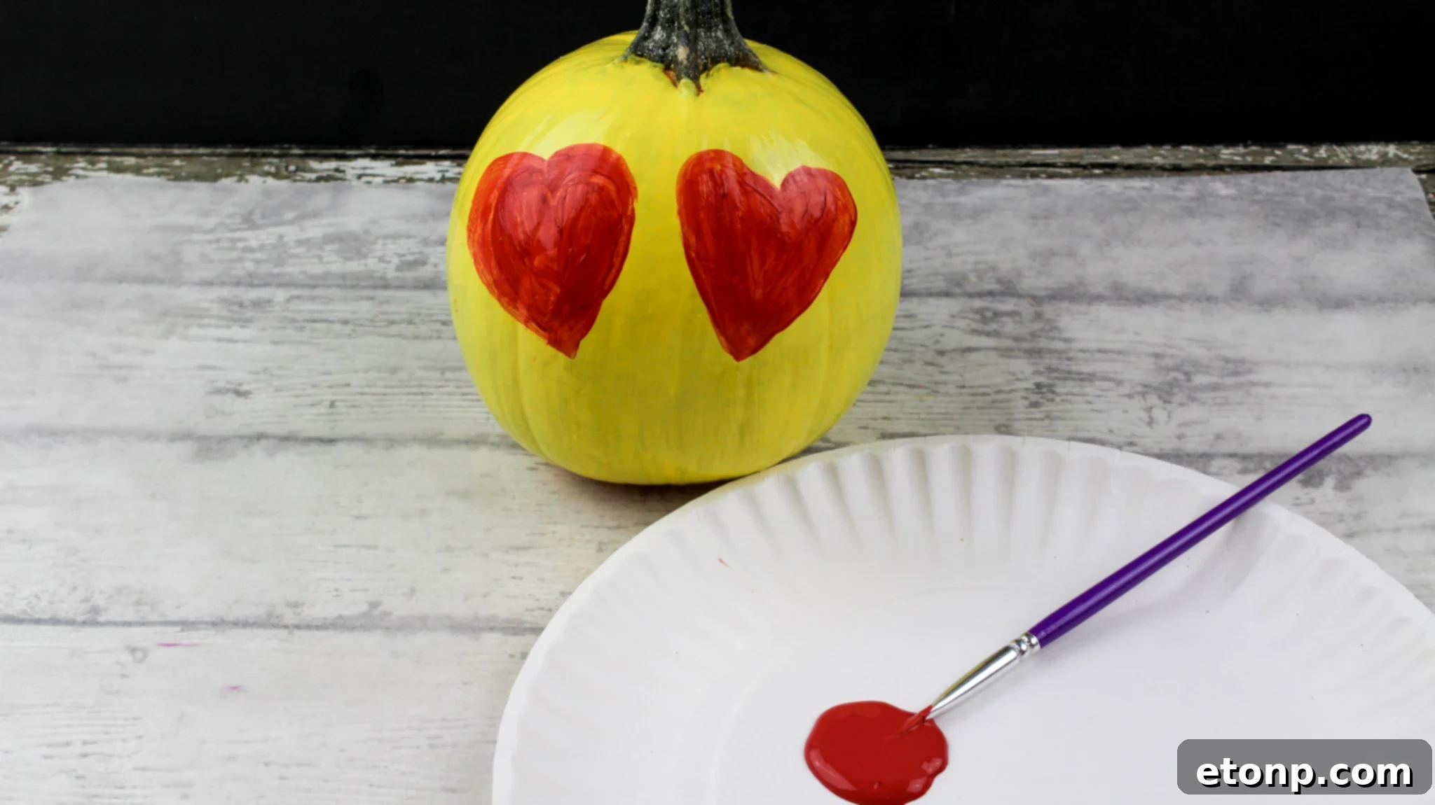 A yellow painted pumpkin featuring a smiley emoji face with black sunglasses, exuding a cool and playful vibe for autumn decor.