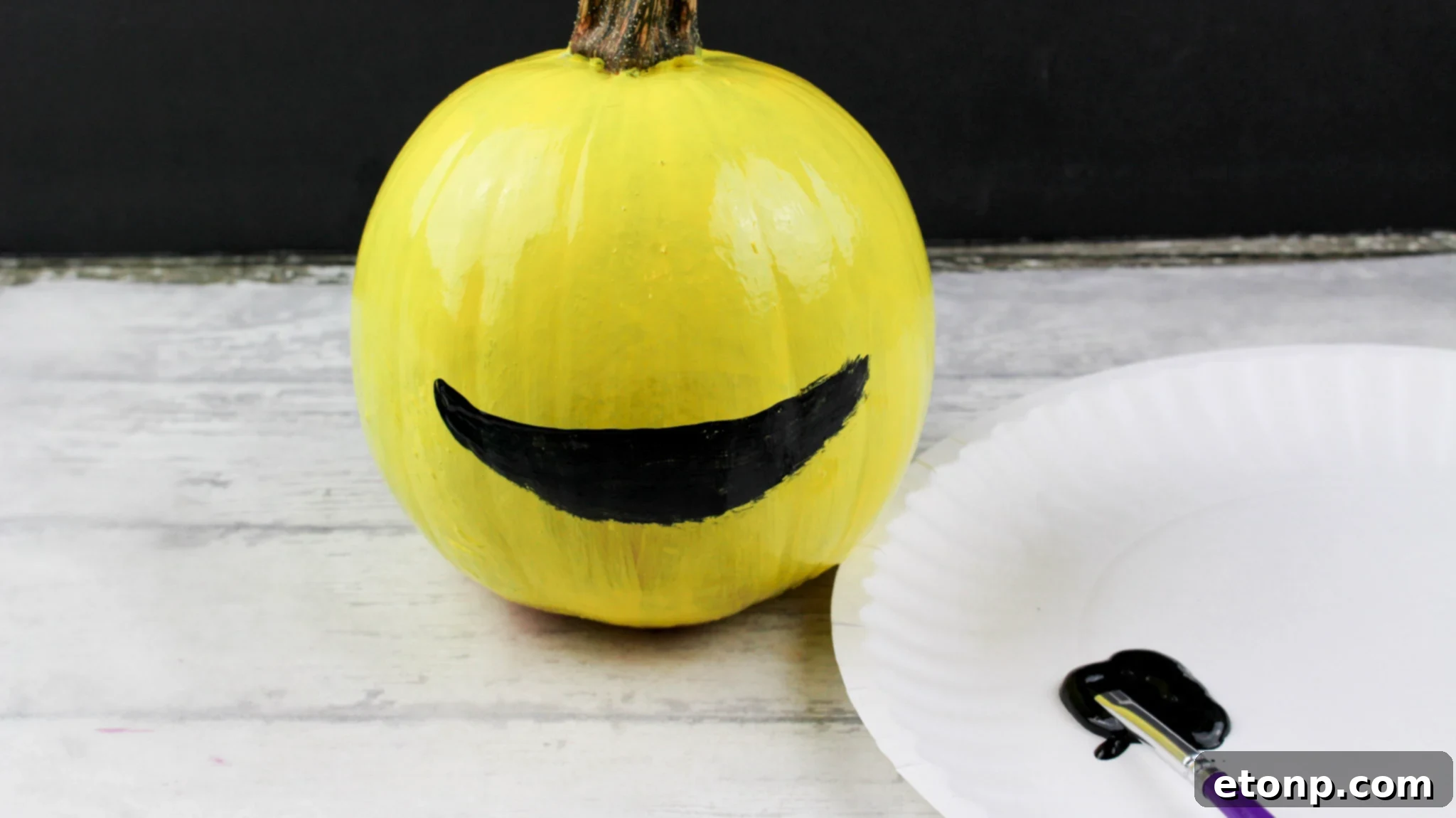 Three yellow painted emoji pumpkins displayed outdoors, each with a different fun expression, adding character to the fall decorations.