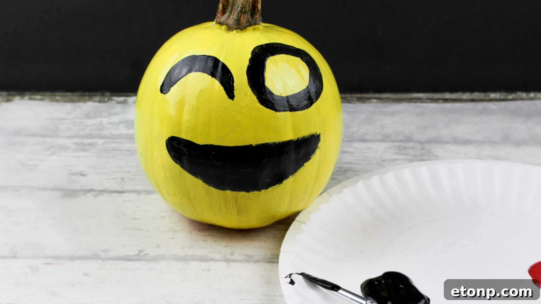 Three yellow painted emoji pumpkins, including heart eyes, cool sunglasses, and a silly winking face, arranged together.