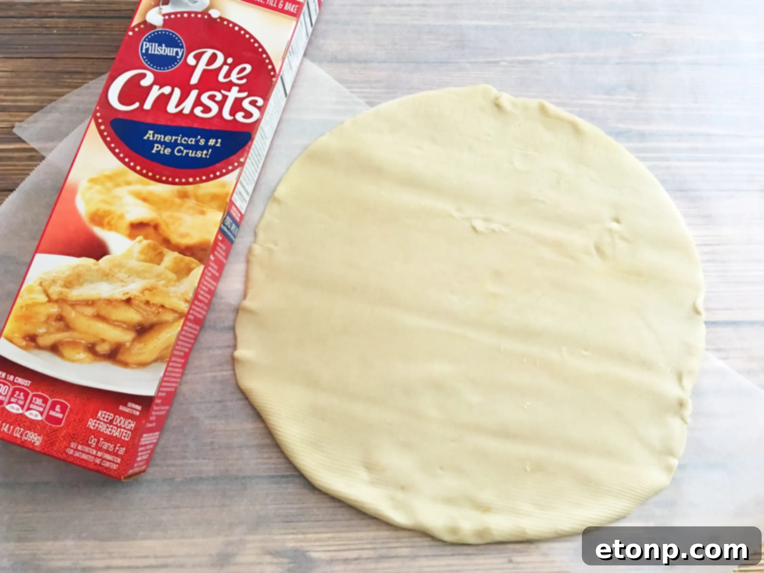 Unrolling refrigerated pie crusts on parchment paper, ready for cutting into festive Halloween shapes.