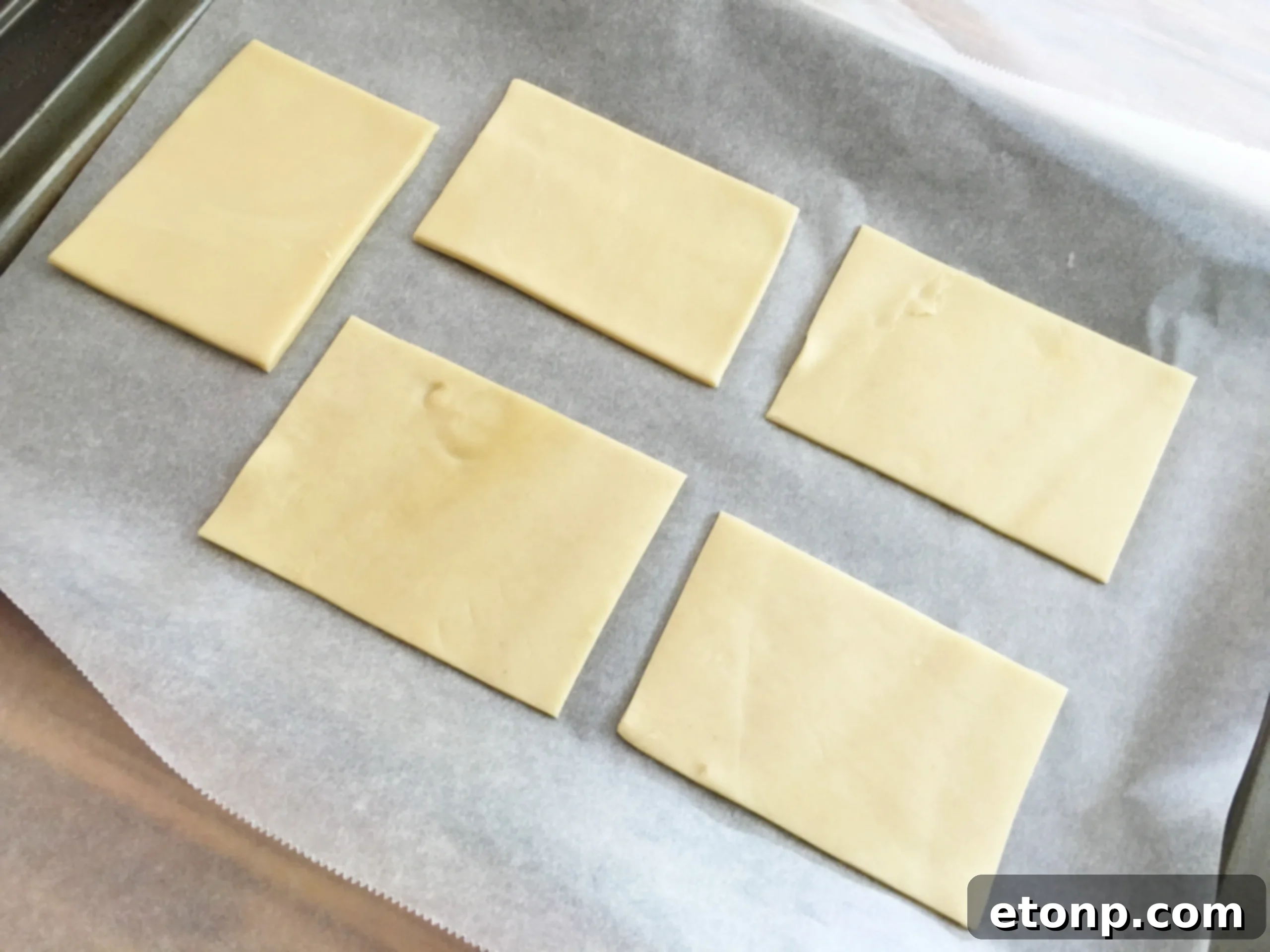 Using a cookie cutter to precisely cut pie crust into small rectangles for mummy hand pie bases.