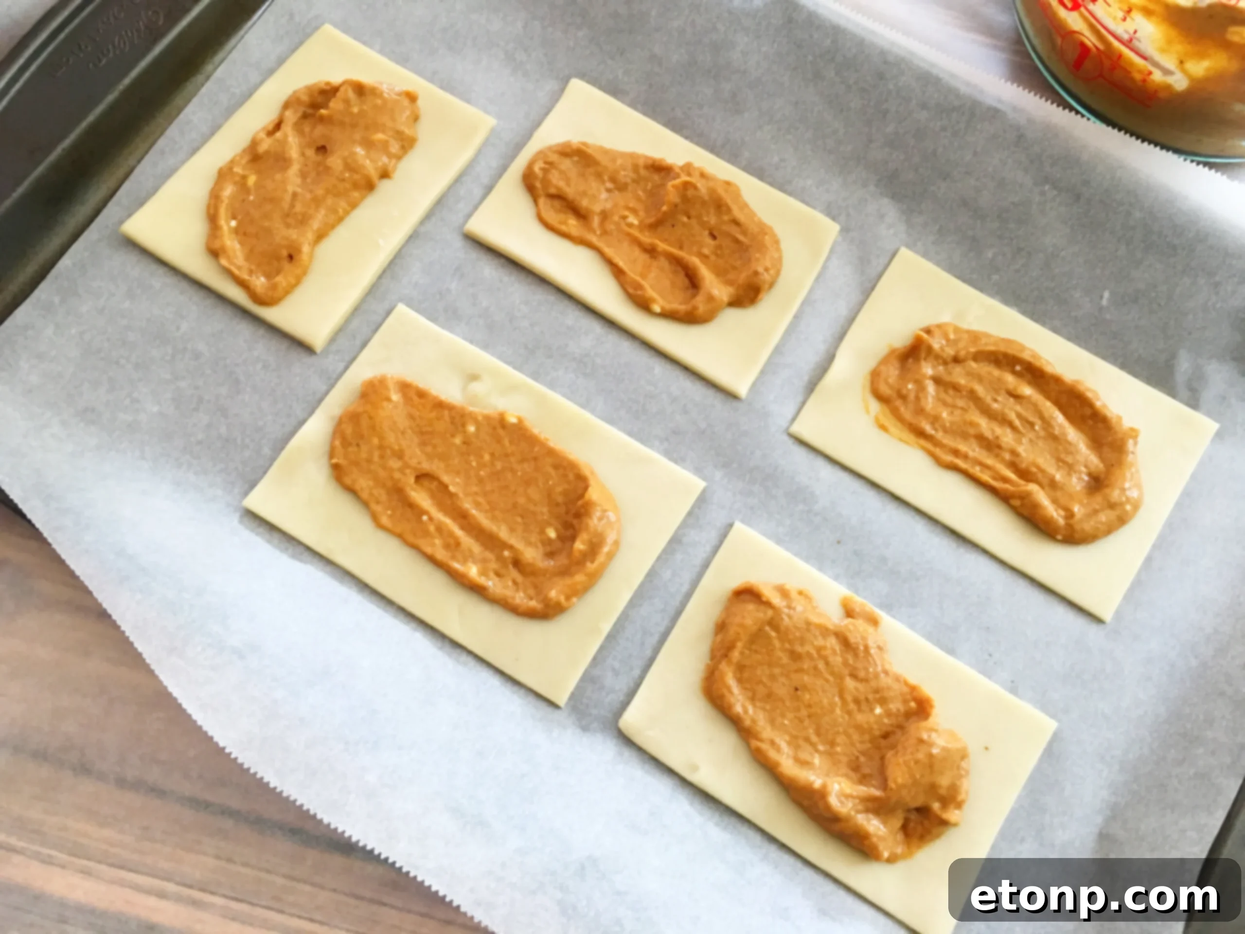 Spreading a generous layer of pumpkin pie filling onto the prepared pie crust rectangles.
