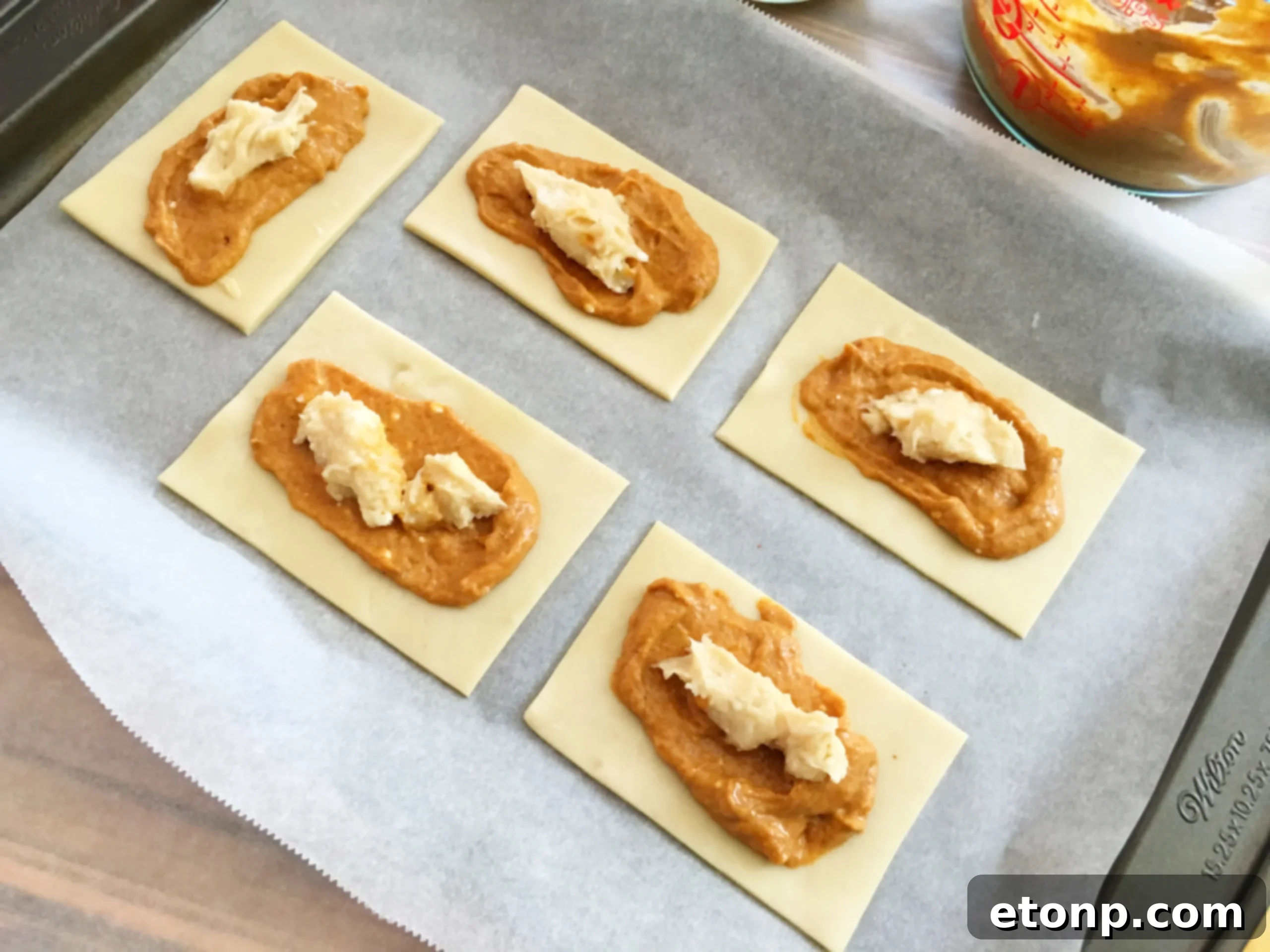 Adding a creamy cheesecake filling layer on top of the pumpkin filling, maintaining clean edges.