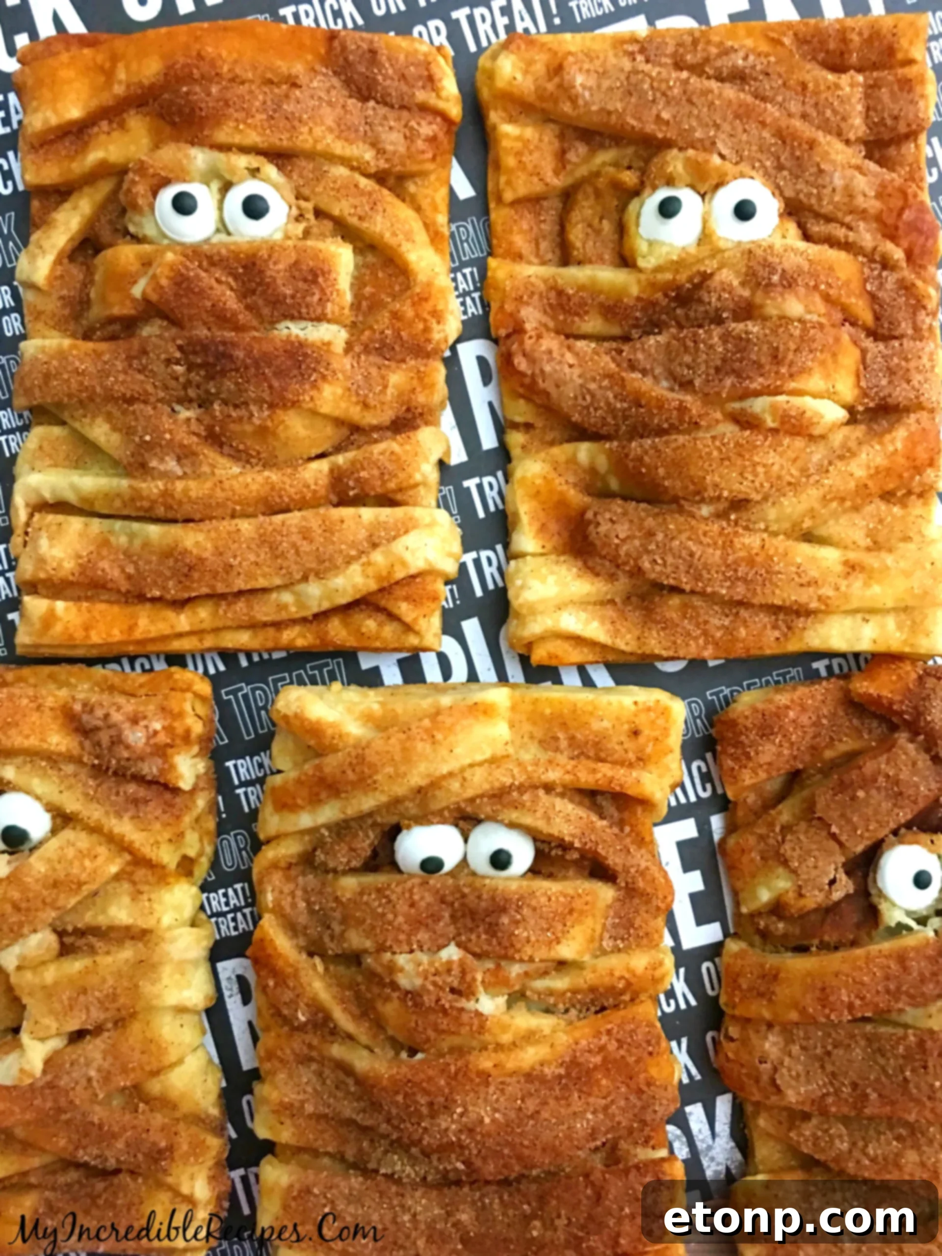 Carefully inserting candy eyes into the small opening on the mummy hand pies, ready for baking.