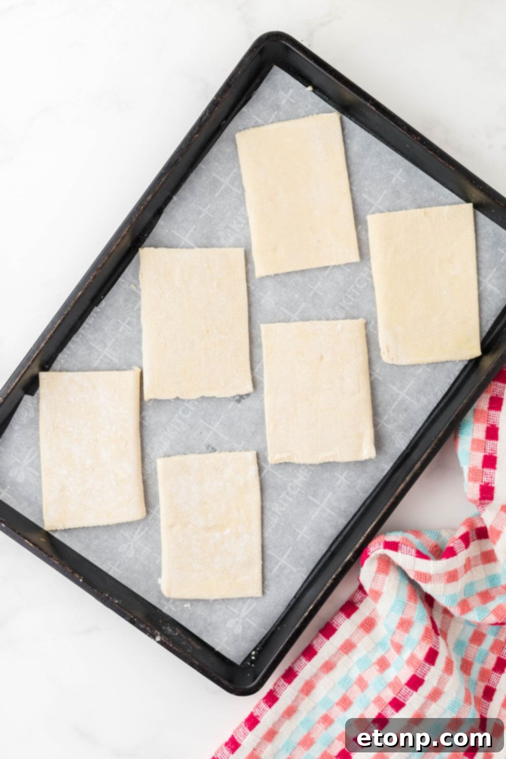 Puff pastry dough neatly sliced into rectangular pieces and arranged on a baking sheet, ready for baking.