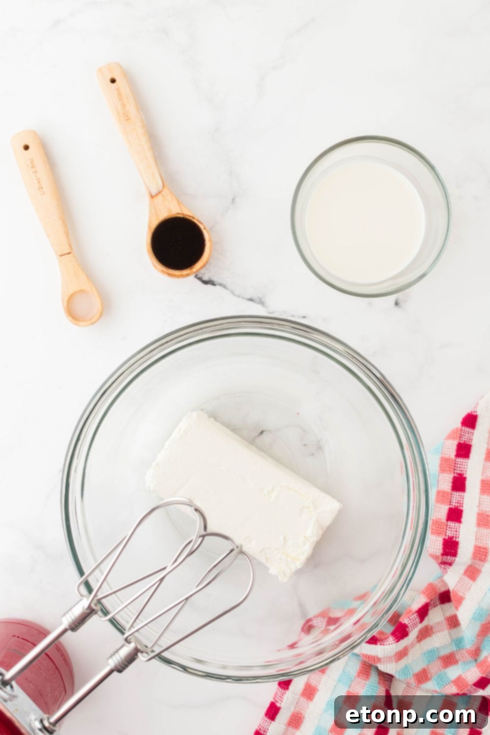 Cream cheese and sugar being blended together in a mixing bowl with a hand mixer, aiming for a smooth, creamy texture.