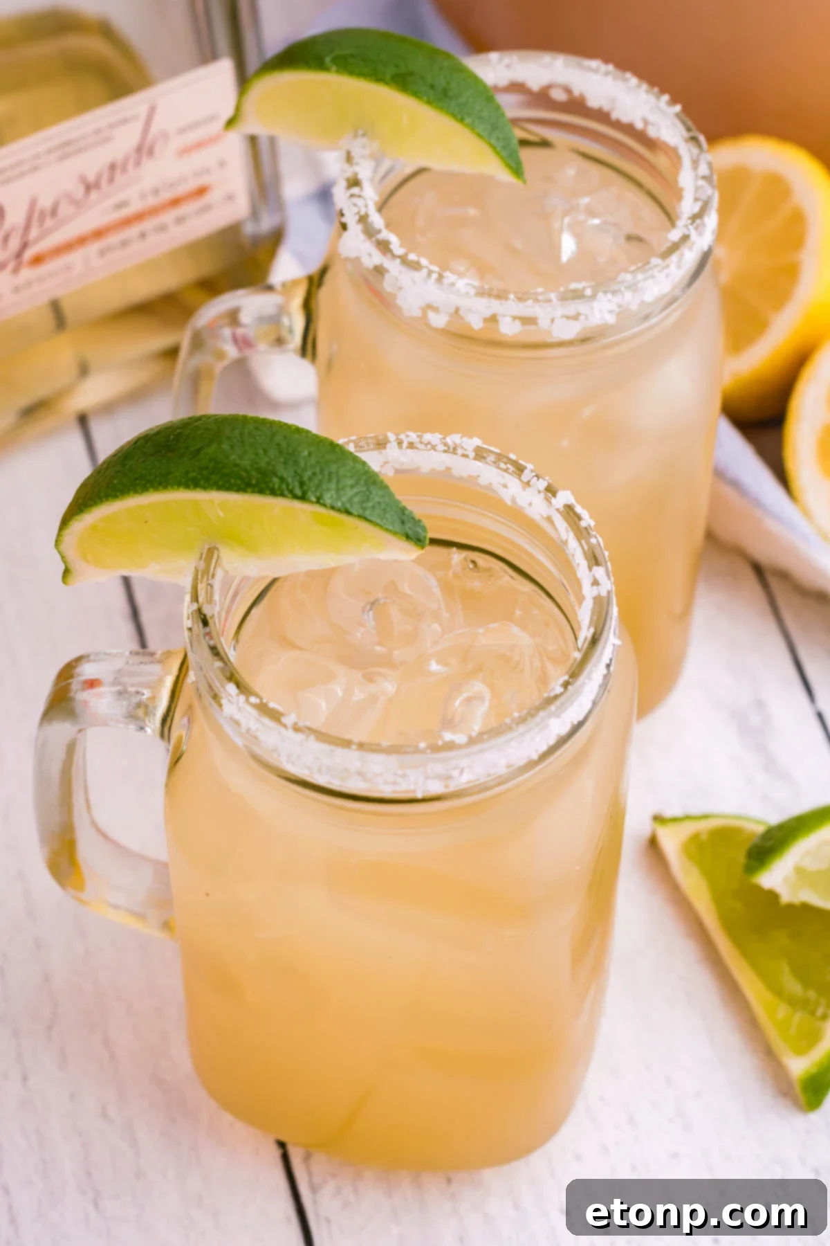 A classic margarita in a salt-rimmed glass, garnished with a lime wedge, sitting on a wooden surface