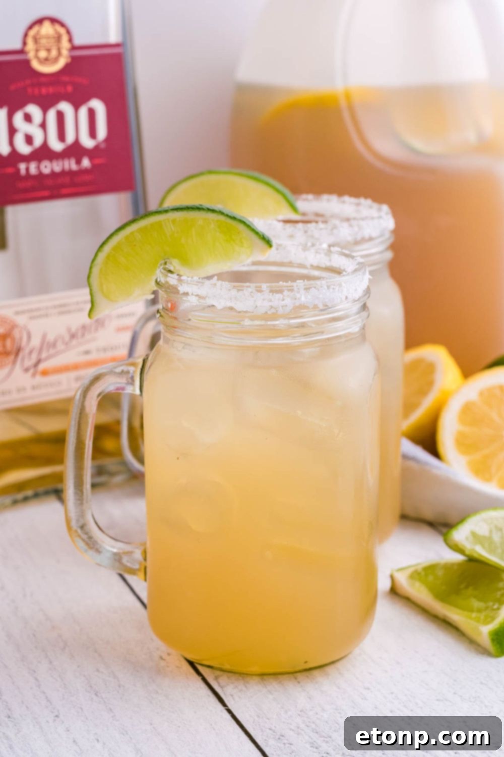 Clear mason jar glasses filled with vibrant margaritas, ready for serving