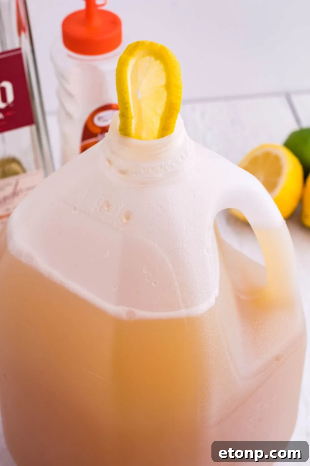 A vibrant lemon wedge placed artfully on top of the margarita mixture in a jug