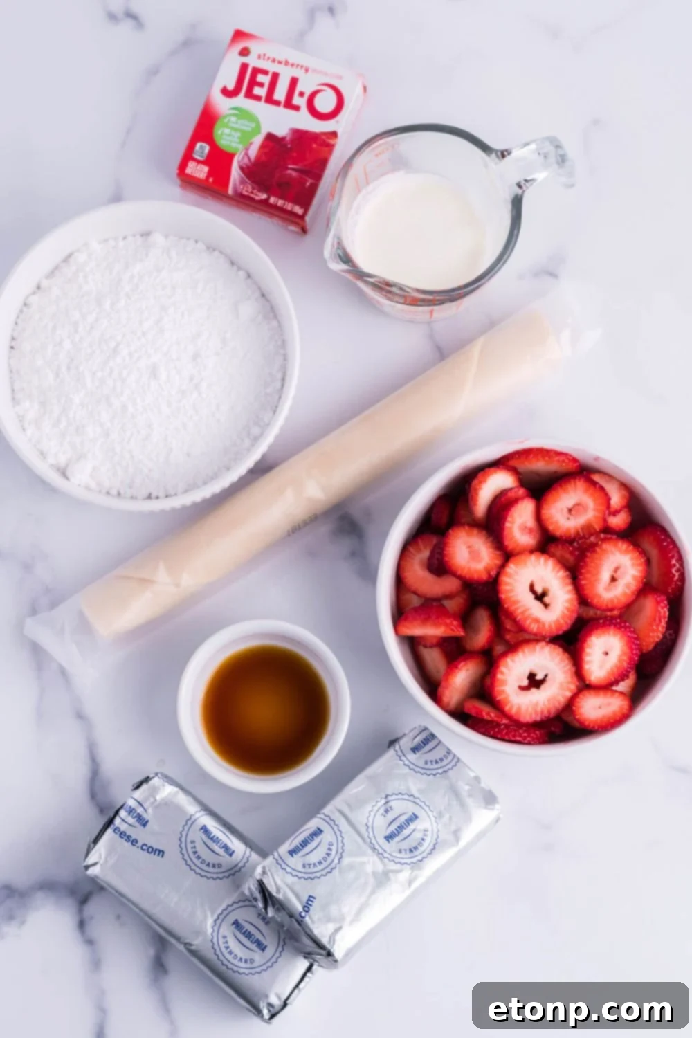 ingredients for a cream cheese and strawberry pie on a marble counter
