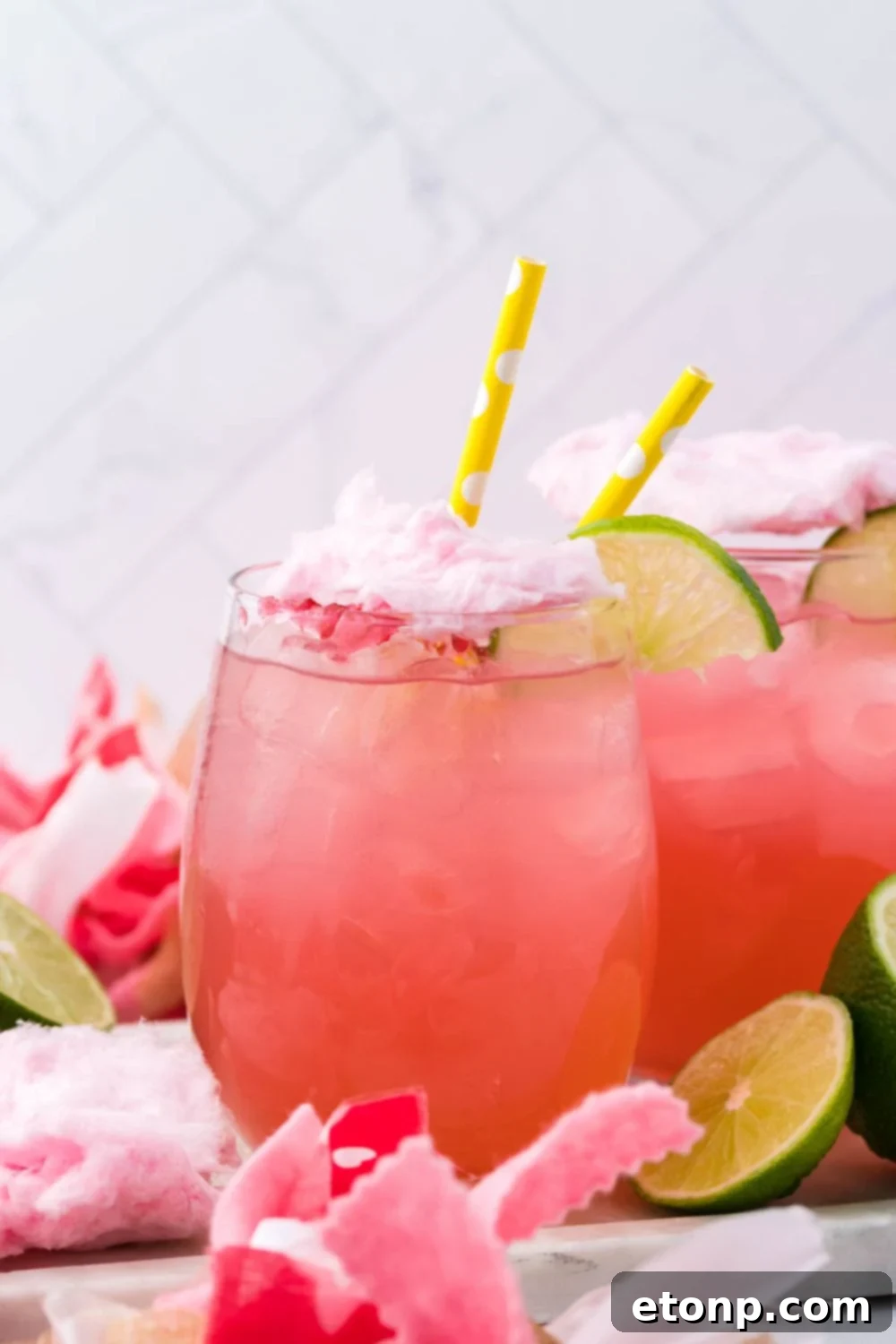 drink with cotton candy on top on table with limes around it