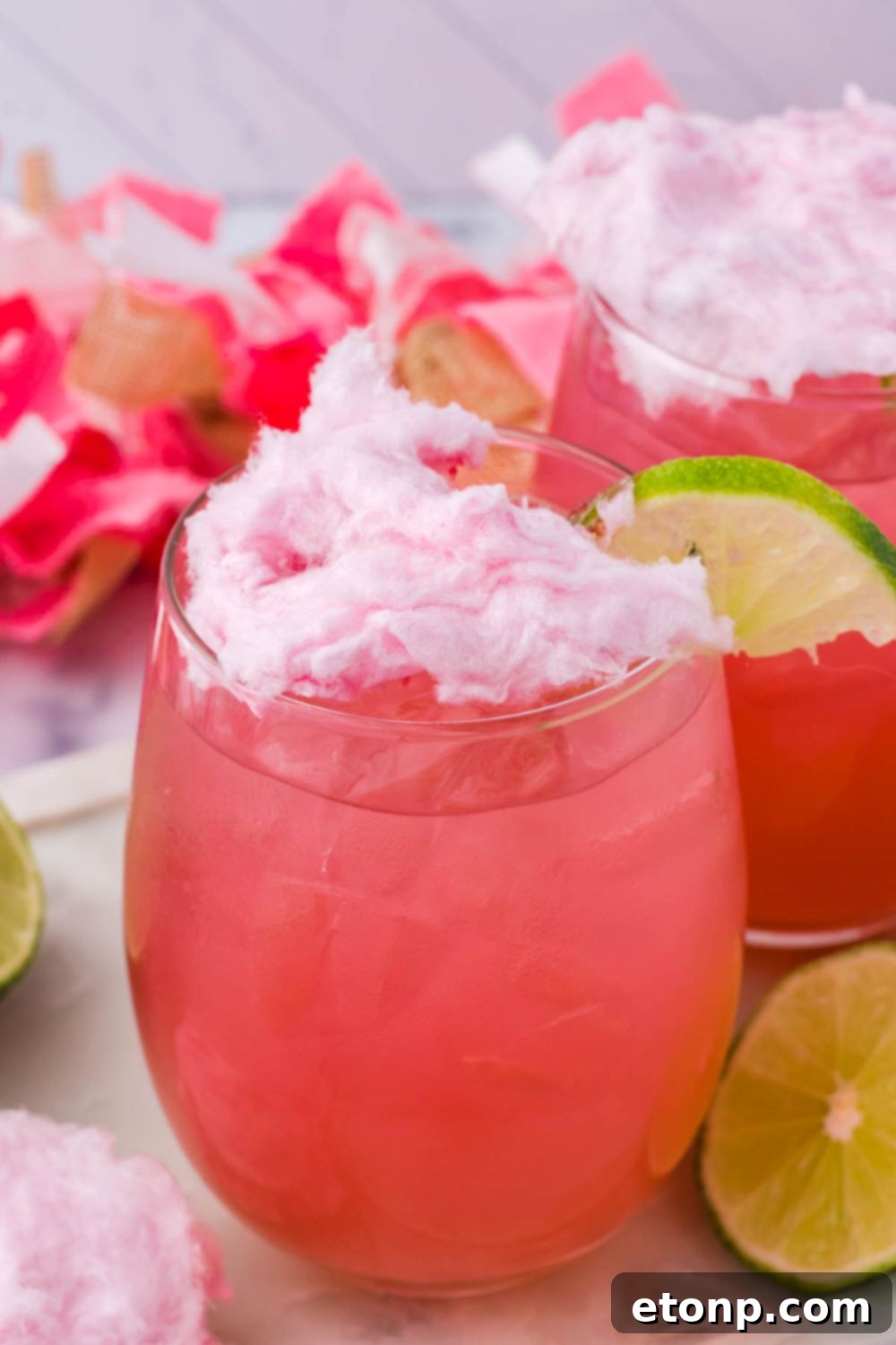 cotton candy on top of cocktail with lime wedge on side