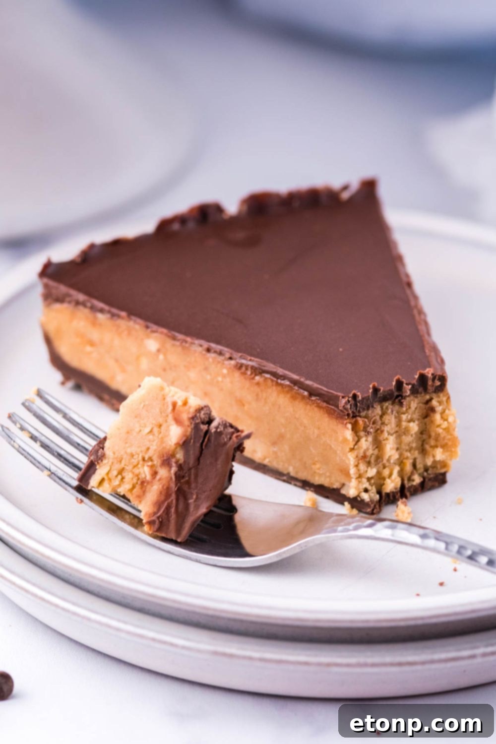 A perfectly cut slice of Giant Reese's Cup Pie on a plate with a fork taking a bite, showing the distinct layers