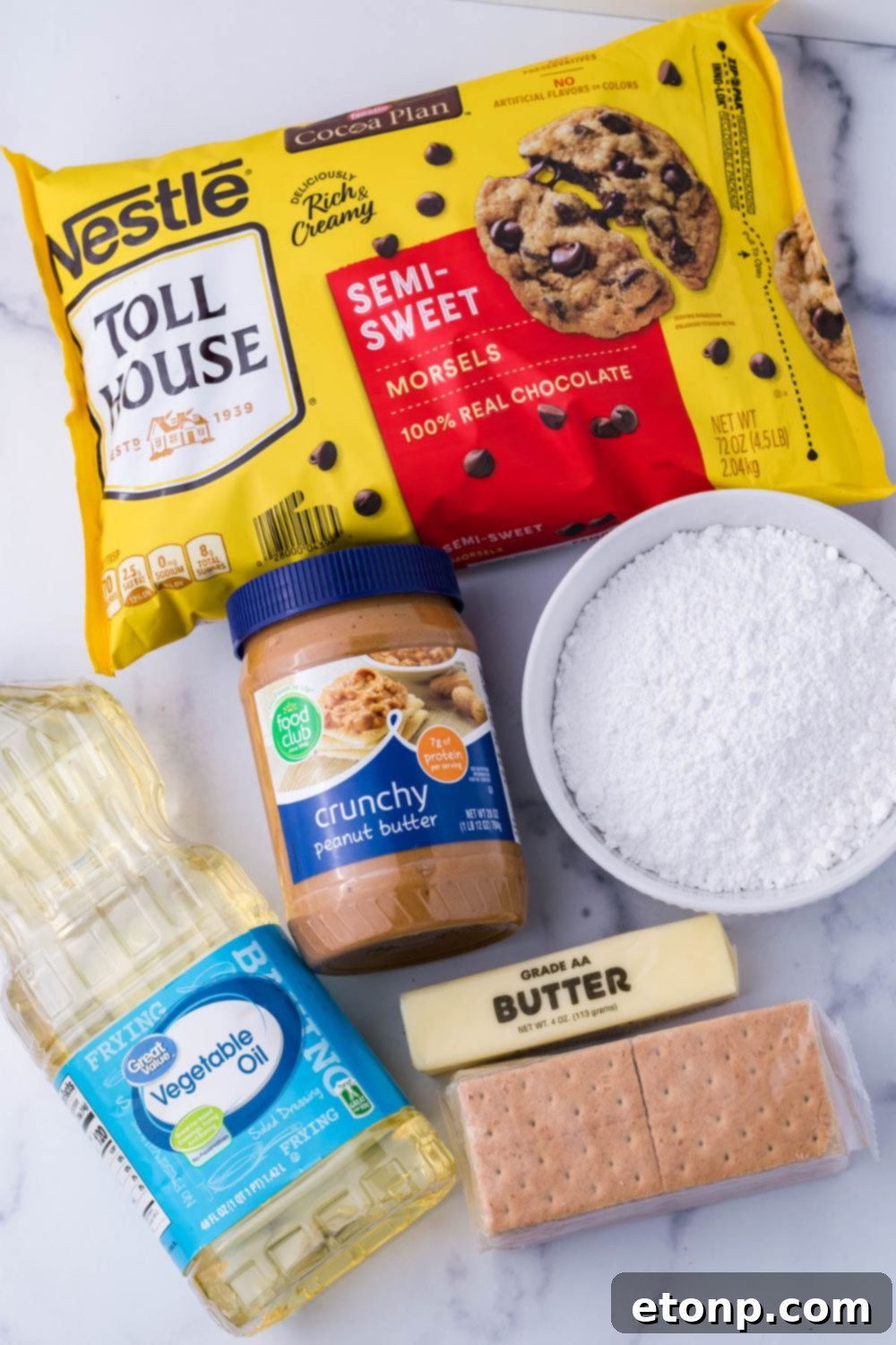 Ingredients for Reese's pie laid out on a table: chocolate chips, peanut butter, graham crackers, powdered sugar, and butter
