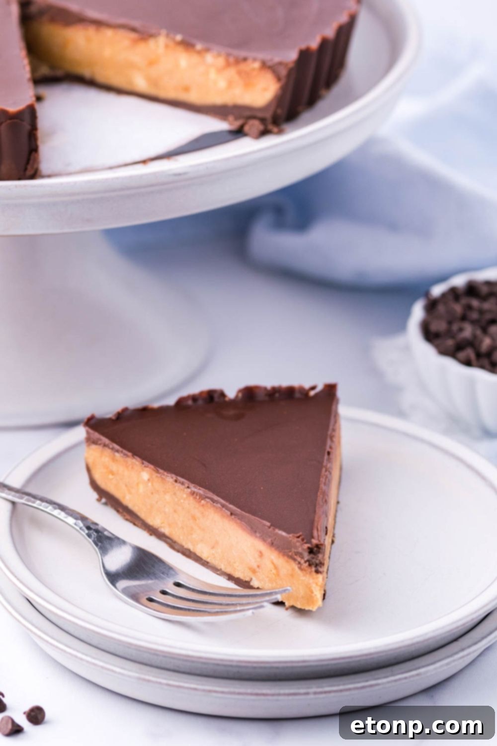 A Giant Reese's Cup Pie on a serving tray, with a slice on a plate and a fork nearby, showing its ready-to-eat appeal