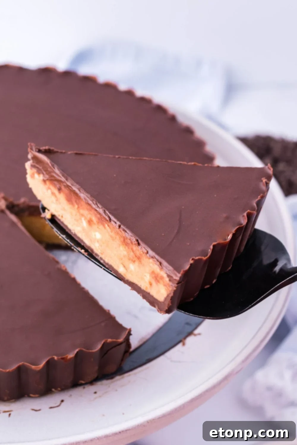 A slice of Giant Reese's Cup Pie perfectly balanced on a spatula, ready to be served