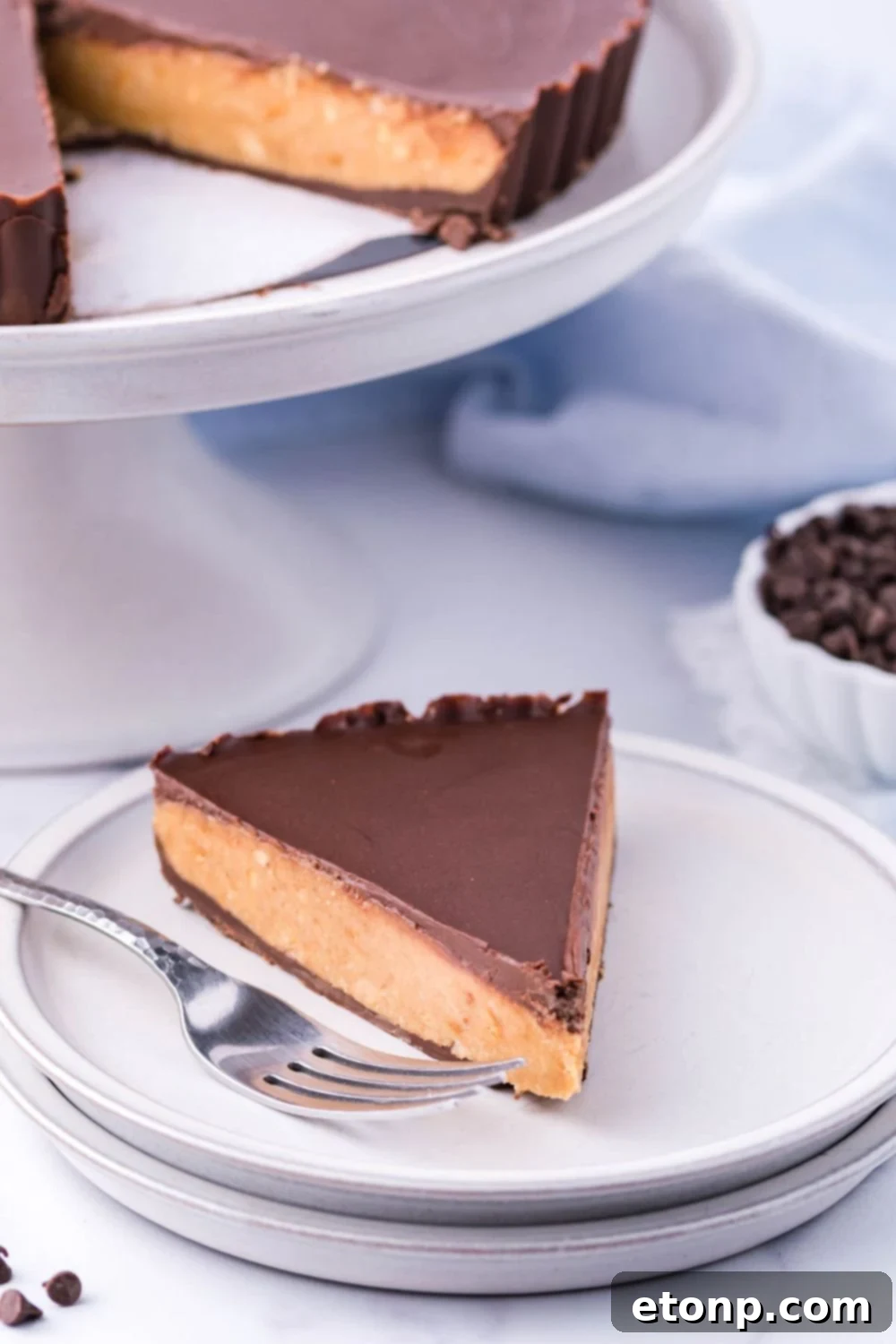 Giant Reese's Cup Pie on a serving tray, with a slice on a plate and a fork nearby, inviting dessert lovers