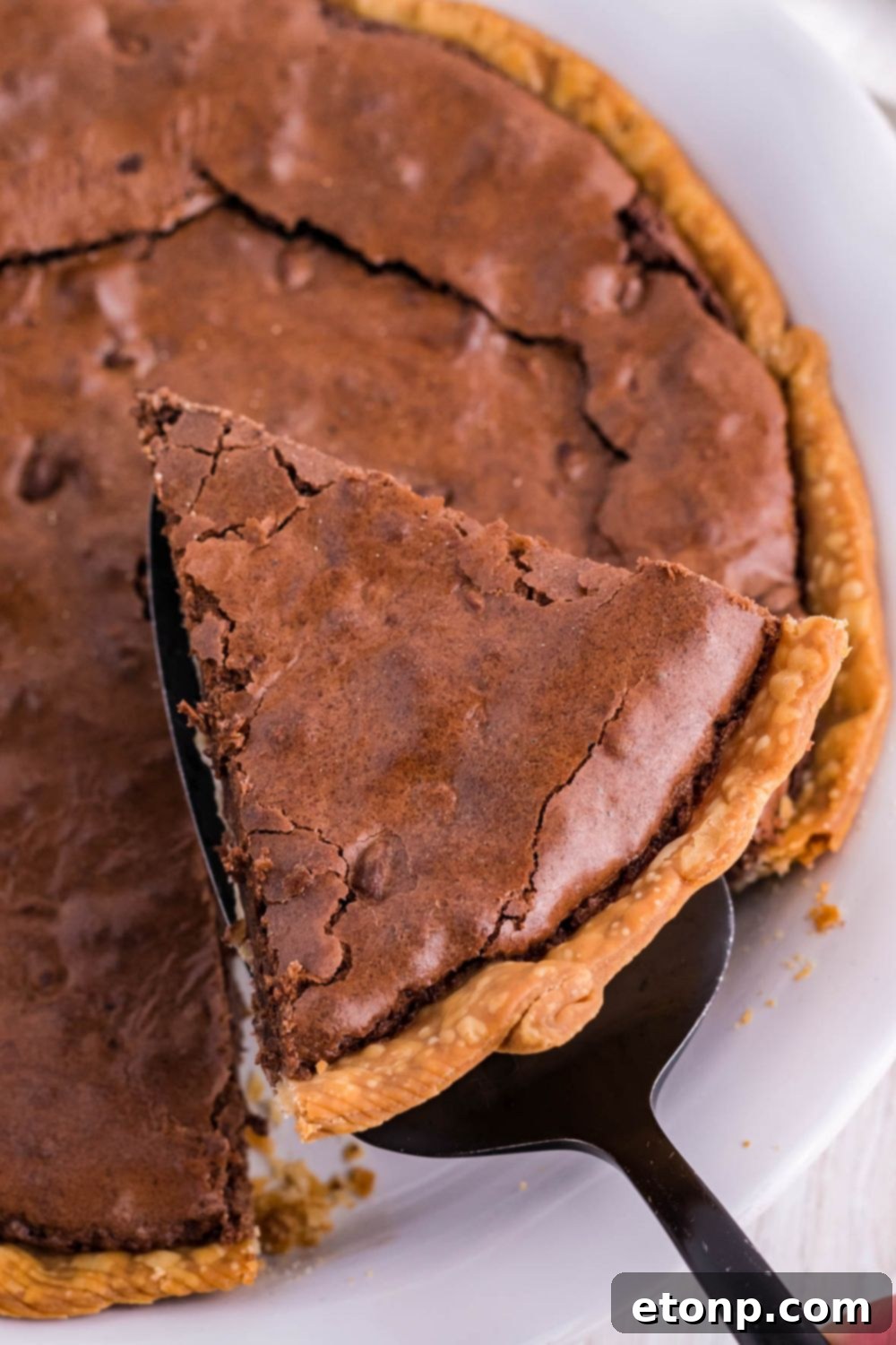 A slice of brownie pie being carefully lifted out of the pan with a pie server, ready to be served.
