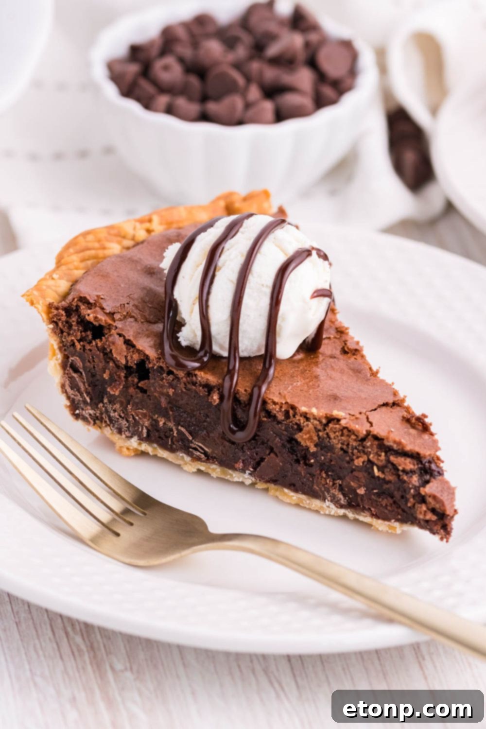 A beautifully presented slice of pie on a plate, adorned with a scoop of vanilla ice cream and drizzled with hot fudge.