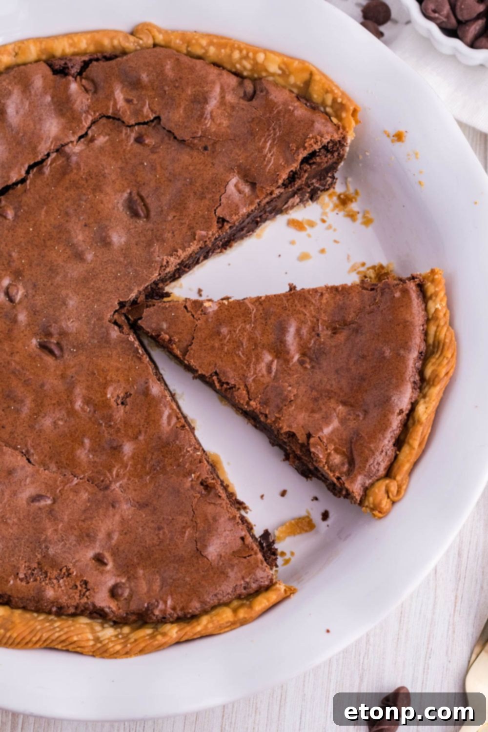 A Fudge Brownie Pie in its pan with one slice already taken, showing the rich texture inside.