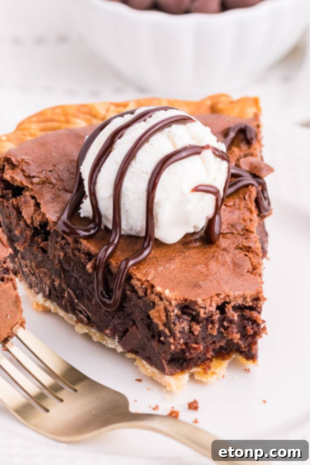 A perfectly sliced chocolate pie on a plate, topped with a scoop of melting vanilla ice cream, ready to be enjoyed.