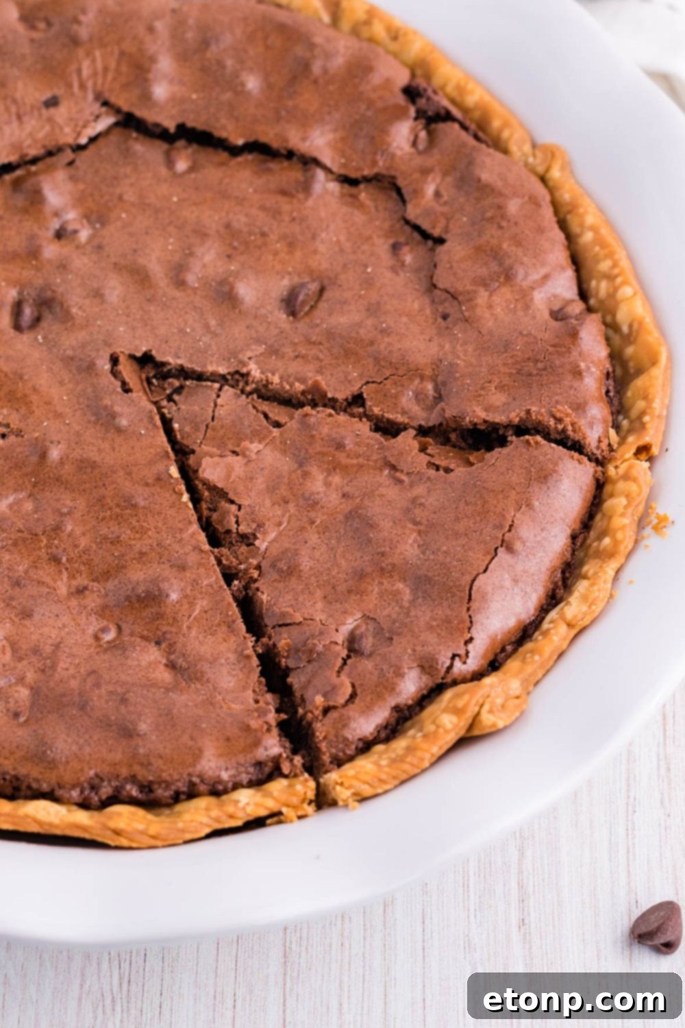 A whole chocolate brownie pie with a single slice removed, revealing the rich, fudgy interior.