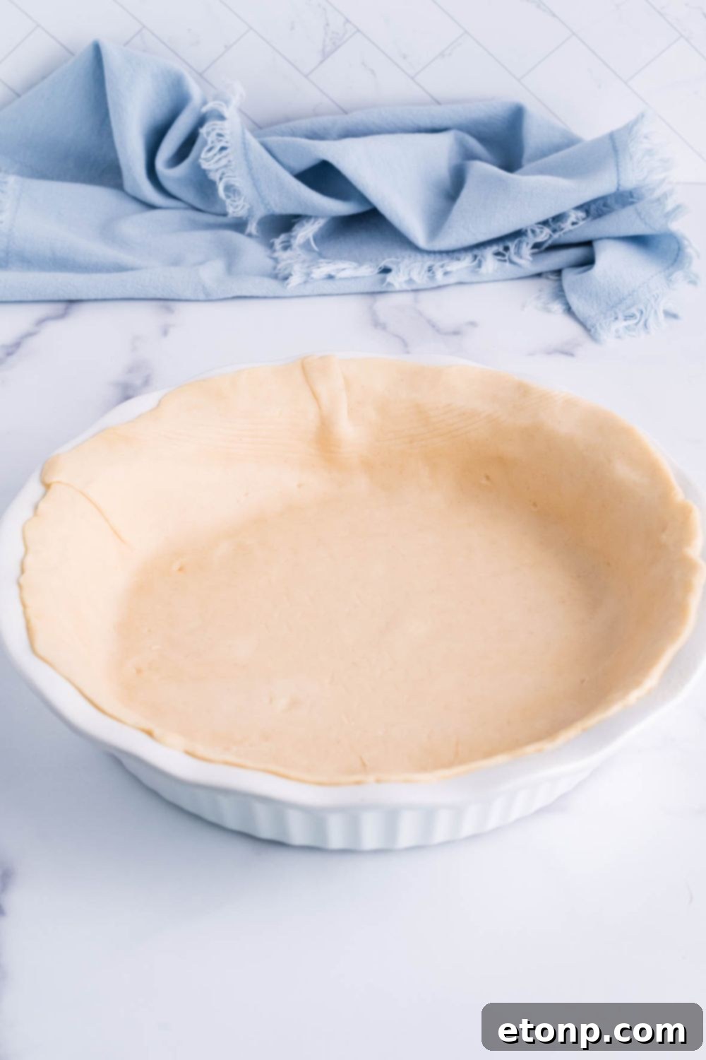 A pie crust neatly placed in a pie pan on a table, ready for filling.