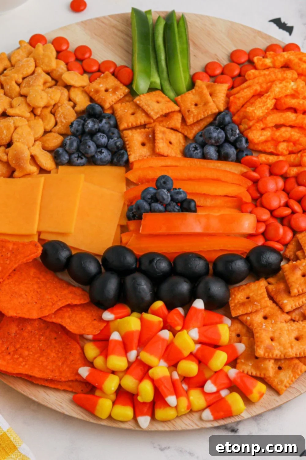 Overhead view of a pumpkin snack board during the assembly process on a round board