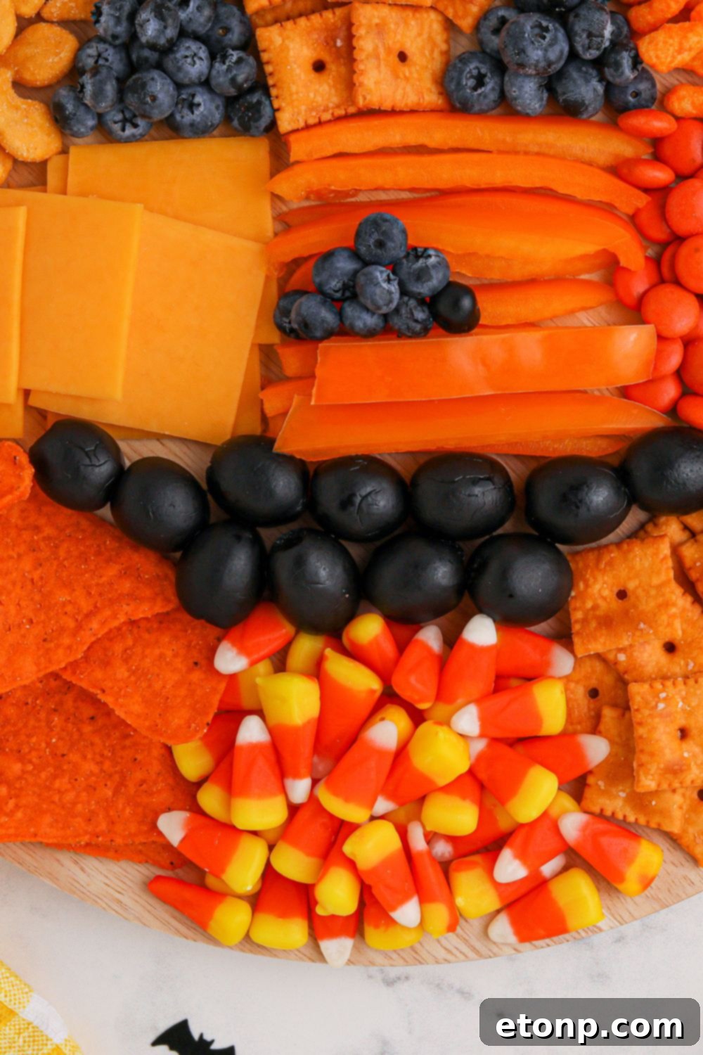 A detailed view of a festive pumpkin-themed charcuterie board with a wide variety of snacks