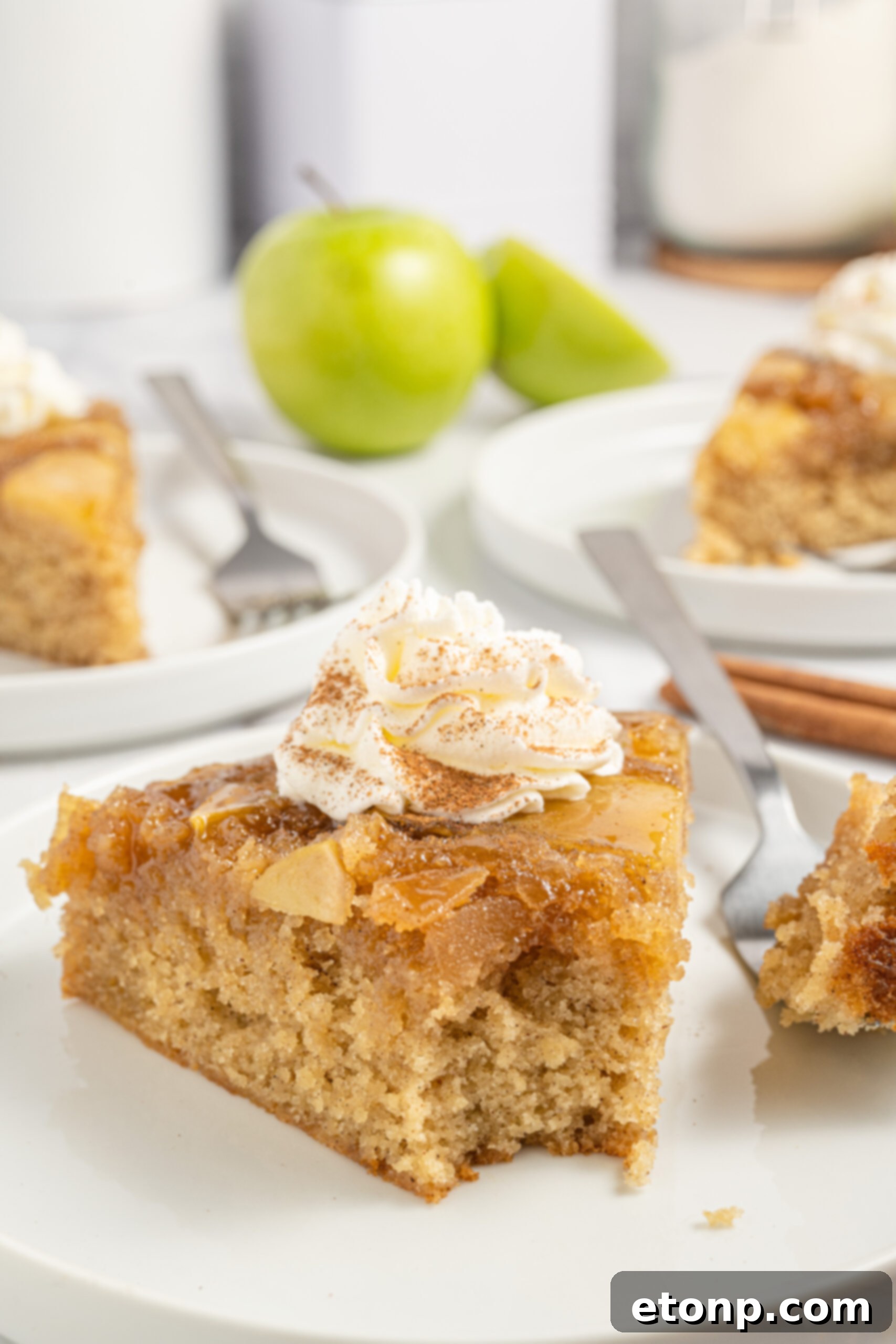 bite taken out of apple spice cake on plate with whipped cream on top 