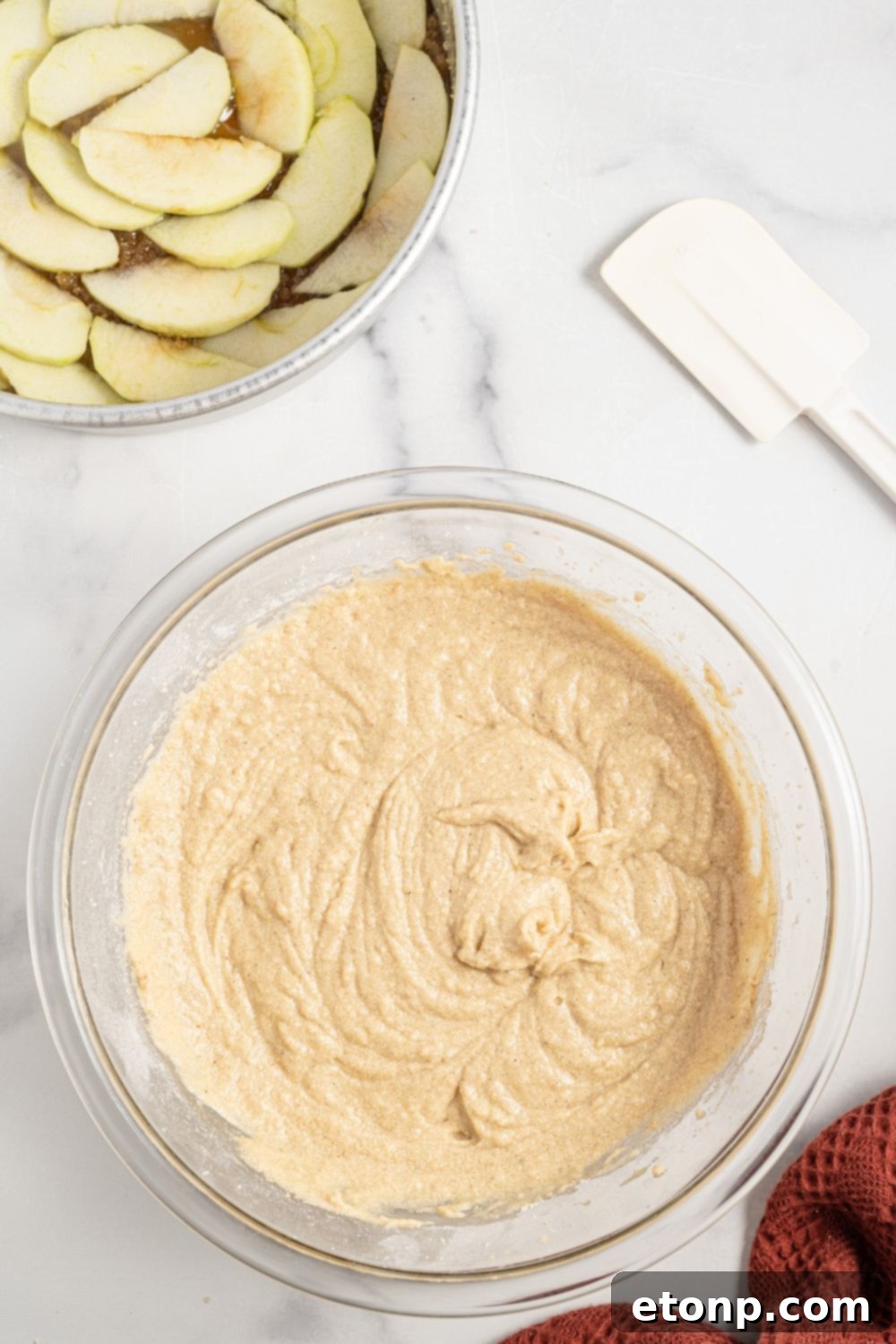 bowl with cake batter and a pan with sliced apples in pan 